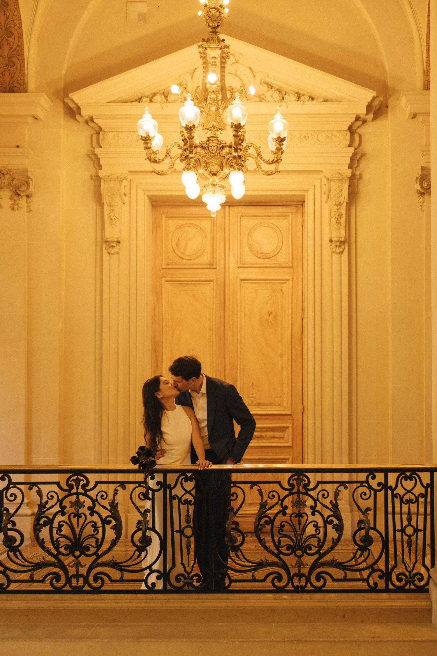 Civil wedding ceremony at Mairie de Levallois-Perret, the couple is kissing under a chandelier of the hotel de ville