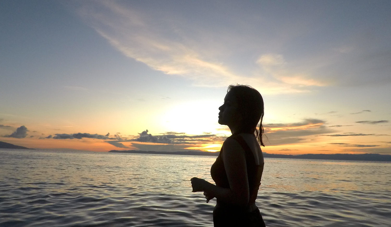 Silhoutte of a girl standing in a beach during sunset