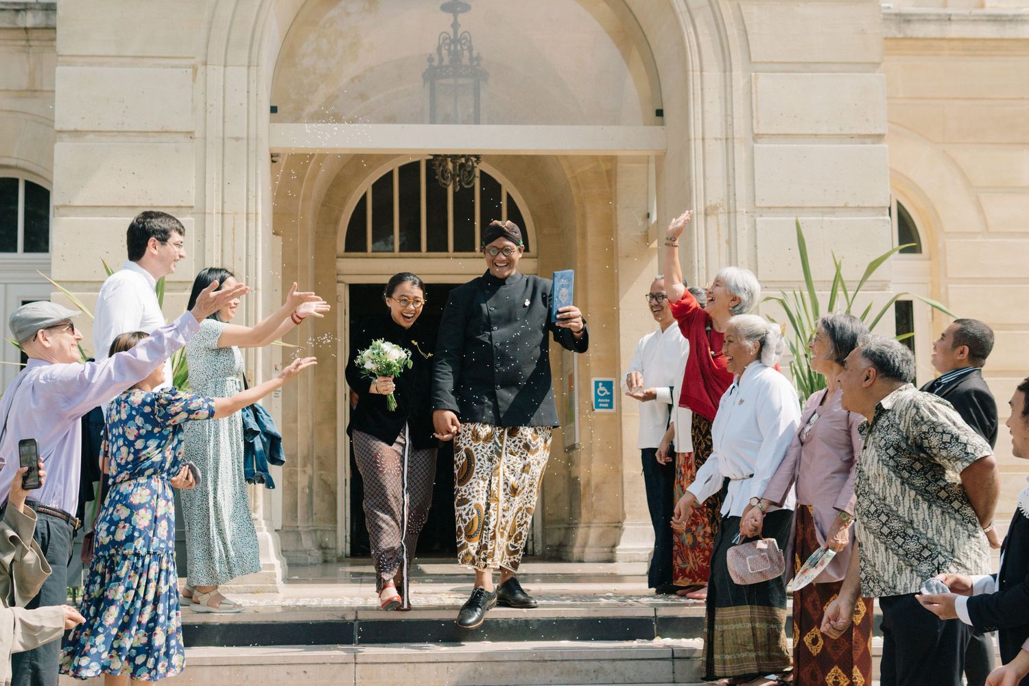 Indonesian civil wedding mairie 14eme paris, the couple is going down the stairs while people throw petals on them