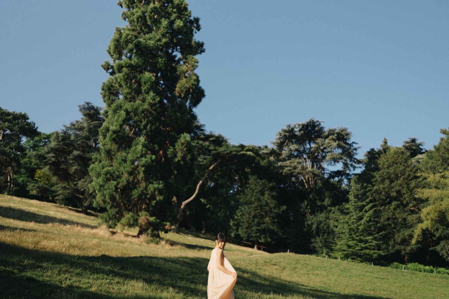 Portrait photoshoot at Parc des Buttes-Chaumont, a girl standing with a trees behind her
