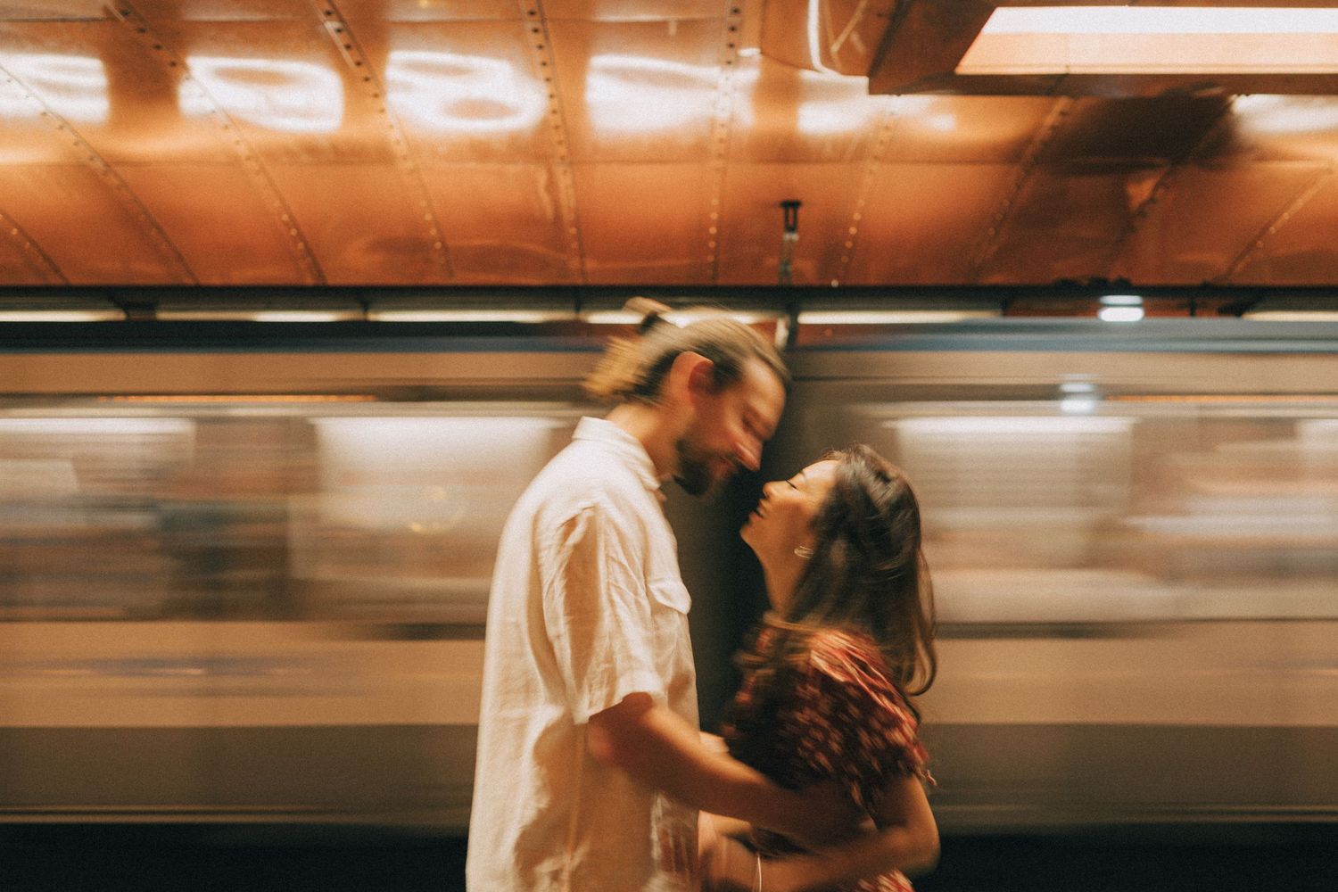 Cinematic photoshoot at metro arts et metiers paris, the couple is about to kiss while a metro is passing behind them