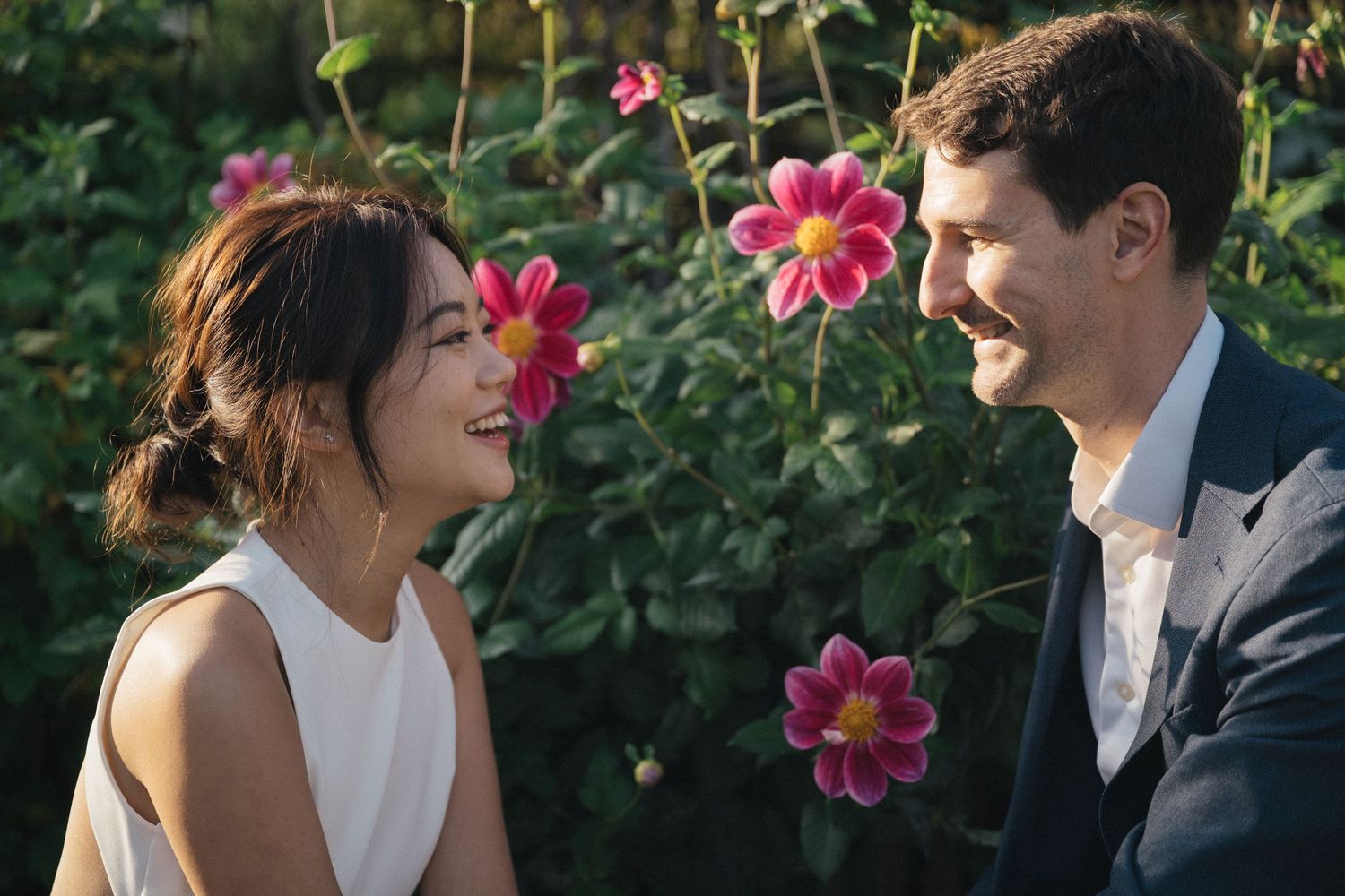 Wedding couple portrait at parc de la planchette, groom and bride laugh in front of flowers