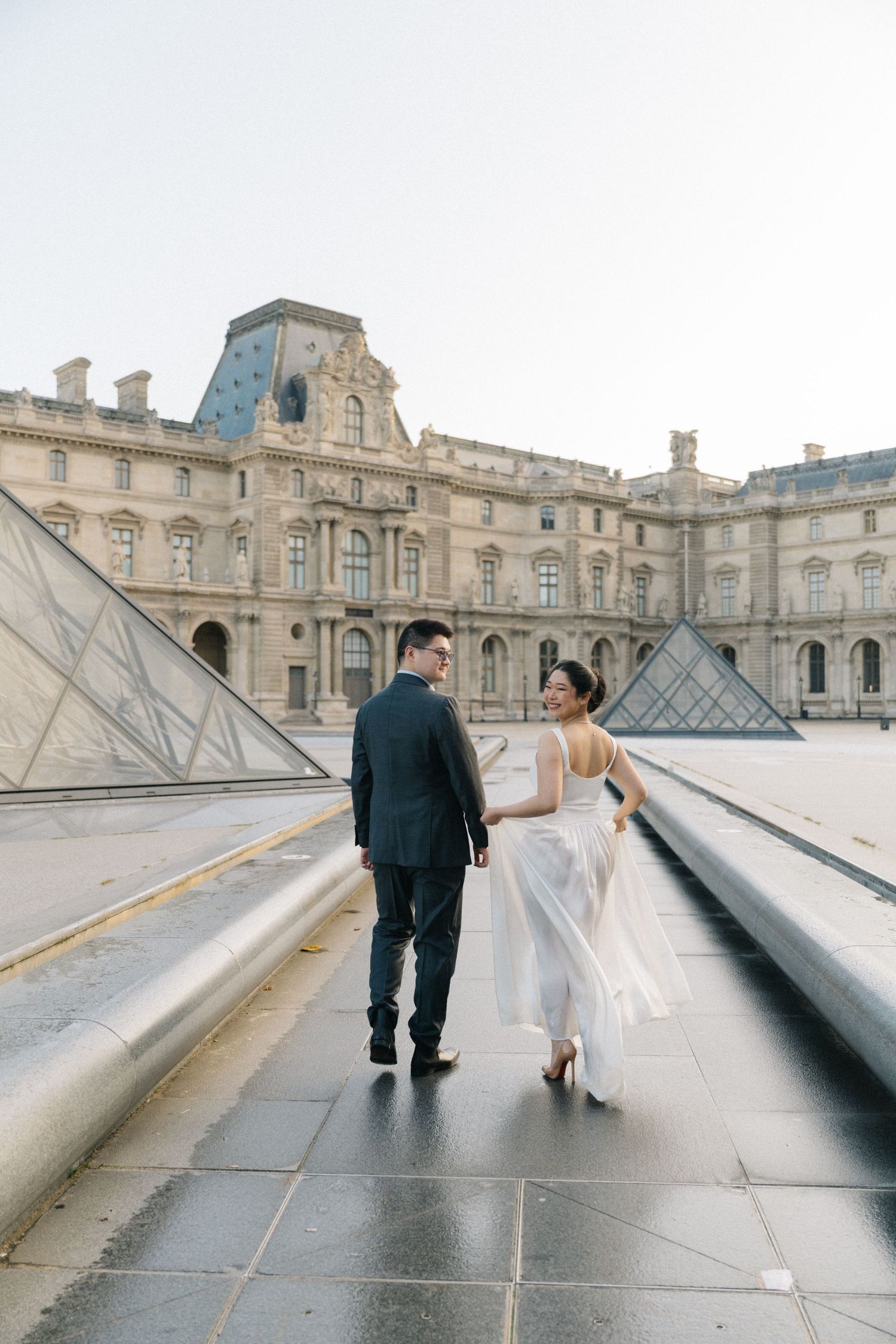 Pre-wedding photoshoot at the louvre pyramid. The bride and the groom is walking.