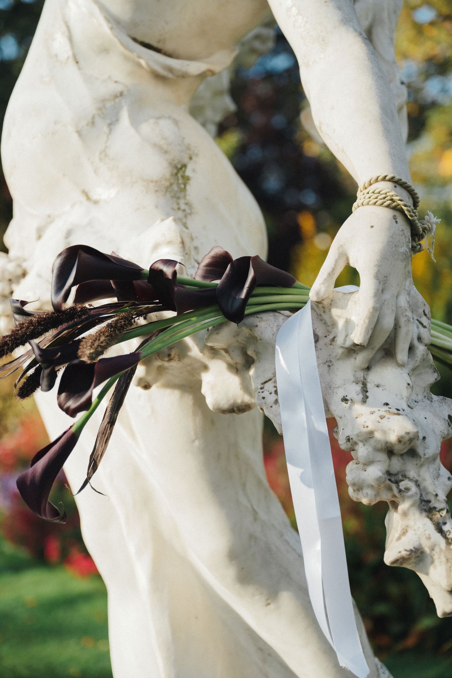 Purple calla lily wedding bouquet on a statue at parc de la planchette
