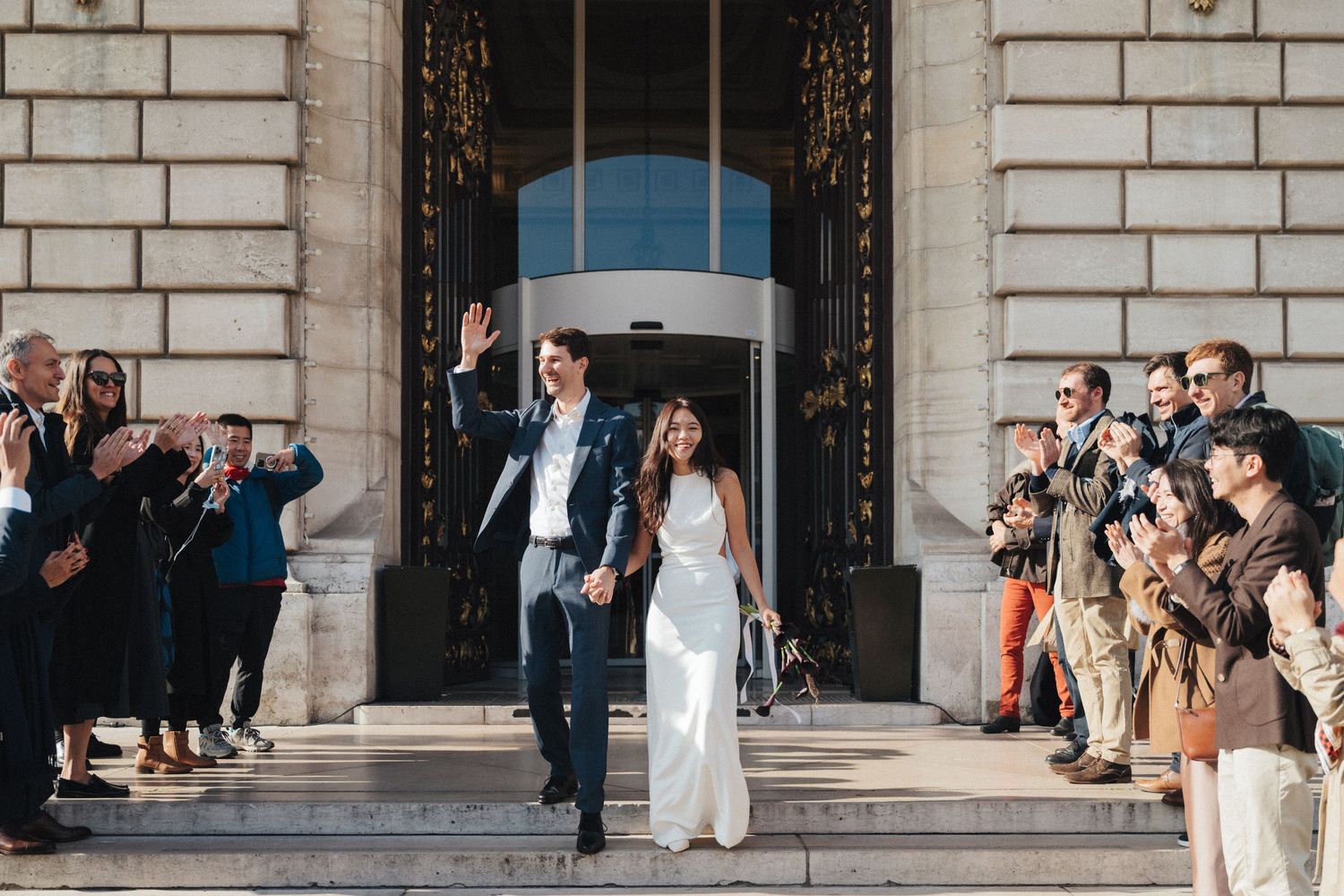 Civil wedding ceremony at Mairie de Levallois-Perret, wedding exit, bride and groom walking down the stairs while their friends cheering