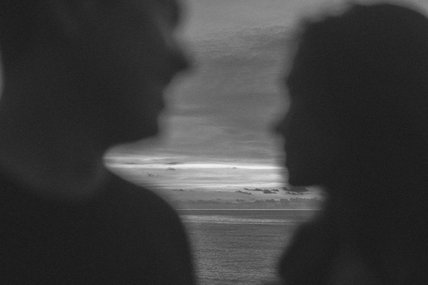 Pre-wedding photo of couple looking at the ocean black and white cinematic