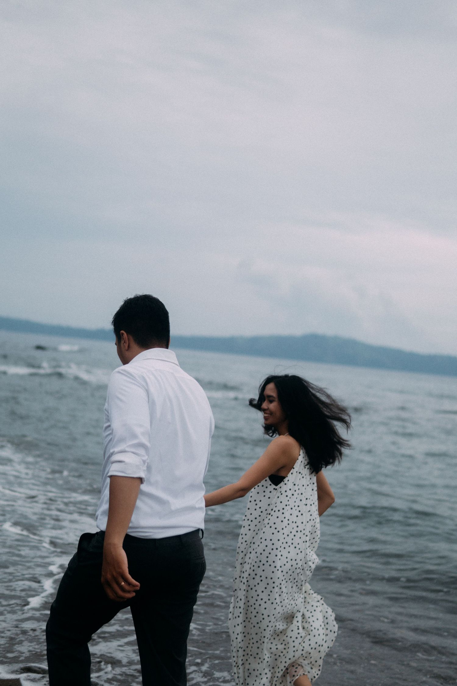 Romantic, cinematic and aesthetic pre-wedding photoshoot of a couple running down on a beach