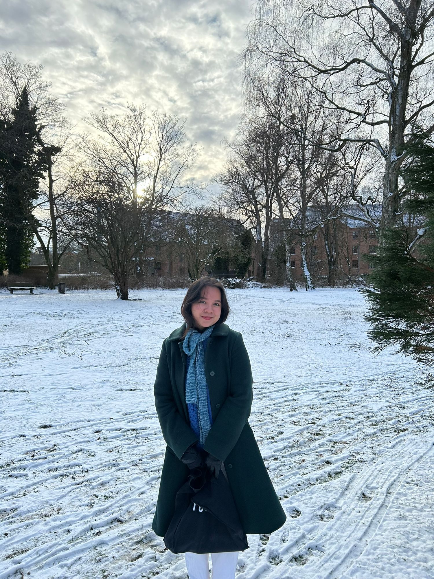 a girl smiling to the camera while wearing green coat, snowy ground