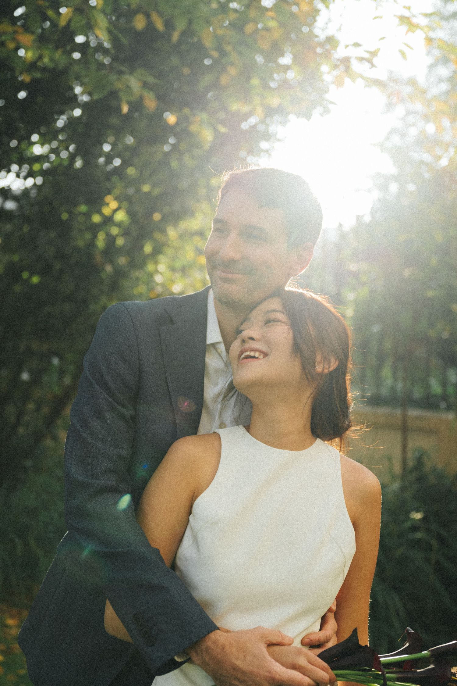 Wedding couple portrait at parc de la planchette, groom hugs the bride from behind