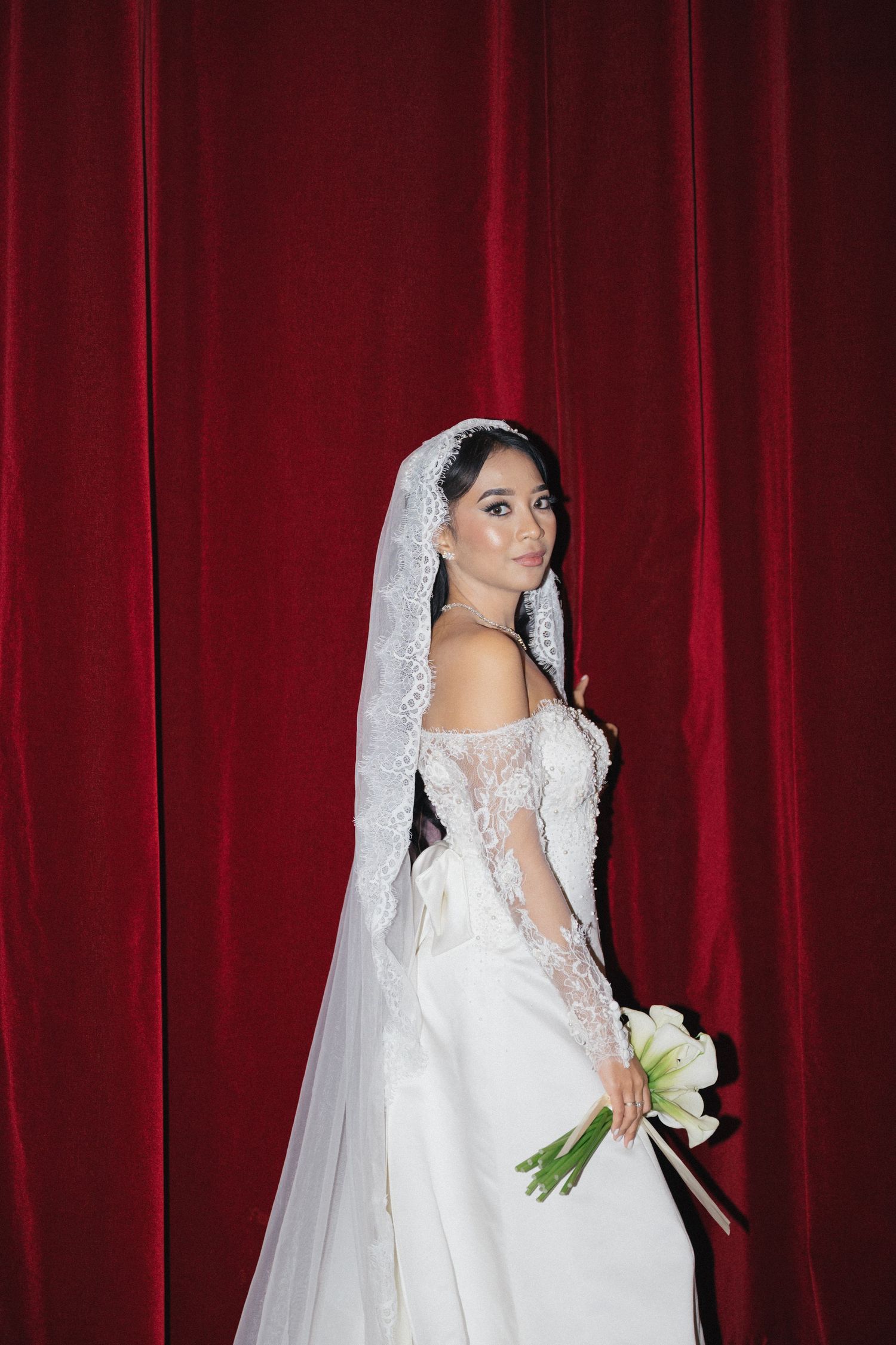 Bridal portraits at American Church in Paris. Bride standing in front of a red velvet cloth backdrop