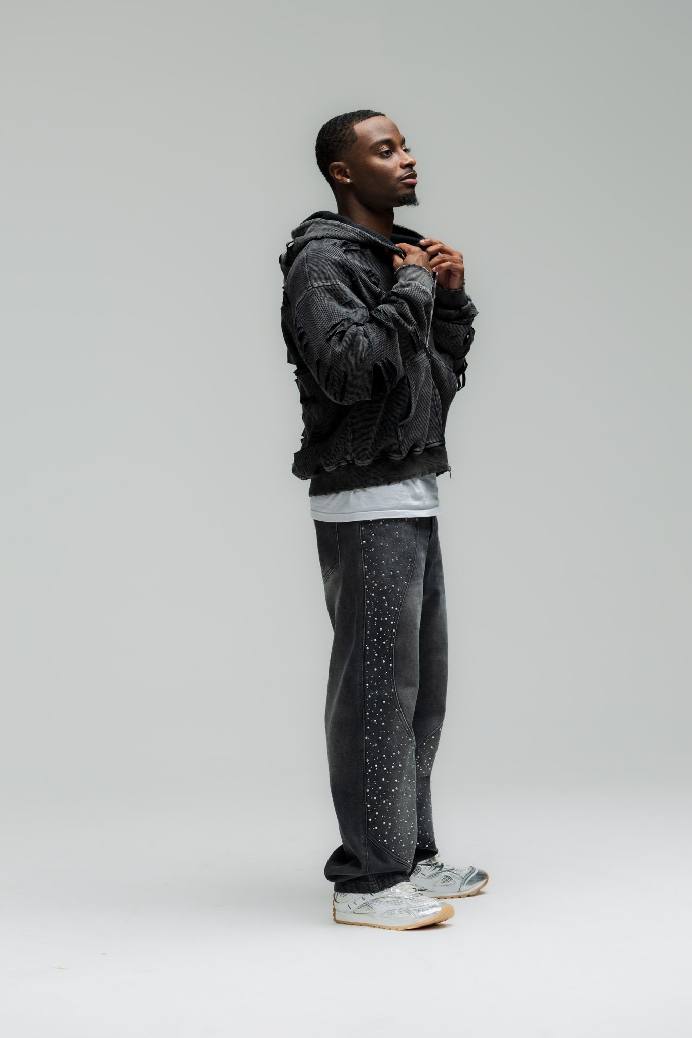 Athletic model wearing black jacket and patterned pants poses against white background in multiple angles.