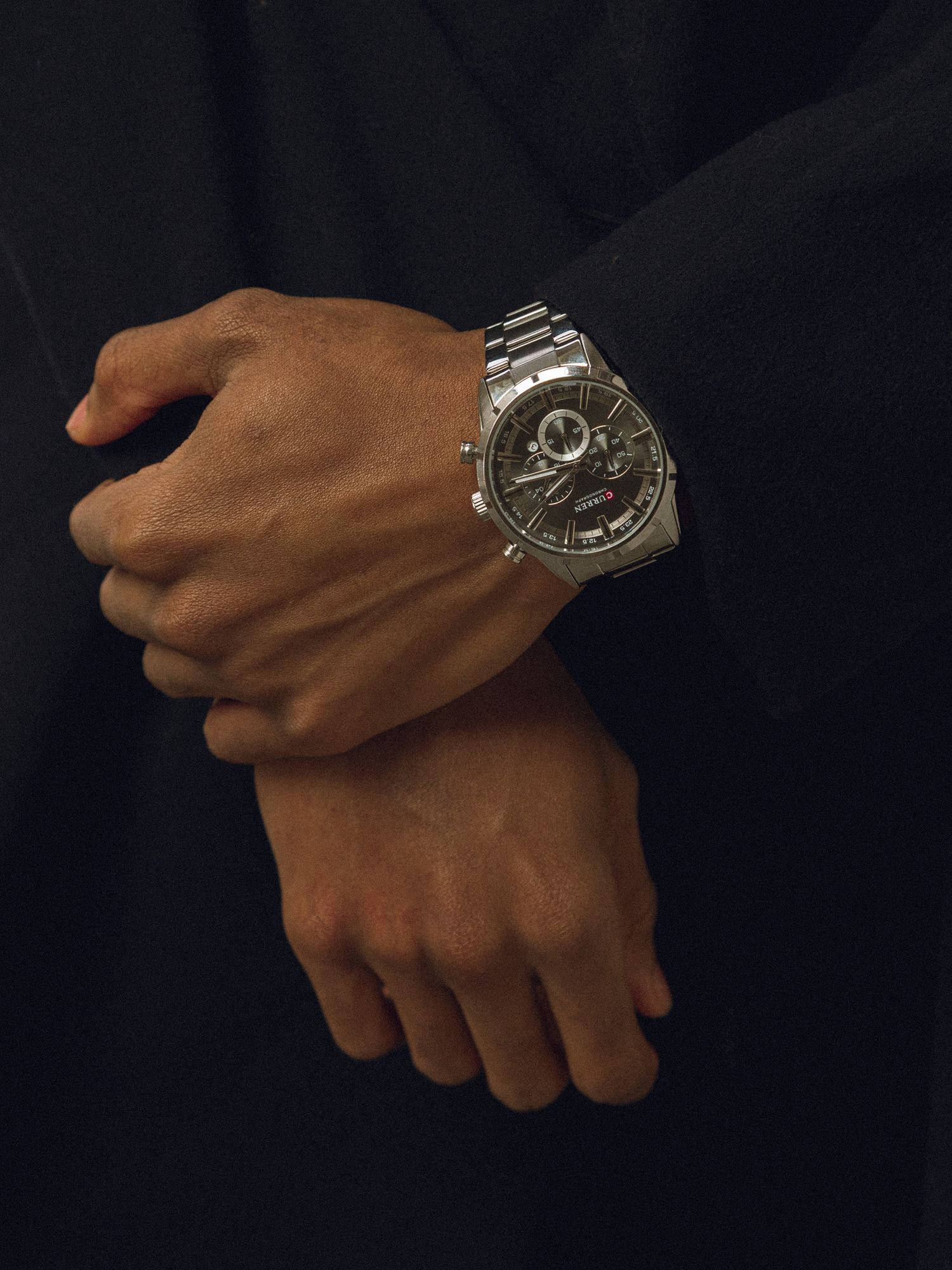A metallic skull ring on a hand shown from multiple angles against a dark background rotates to display its intricate design.