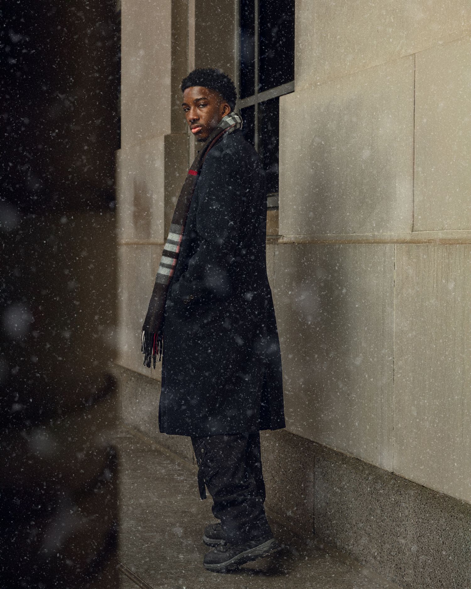 Portrait in winter setting showing person in black coat with falling snow.