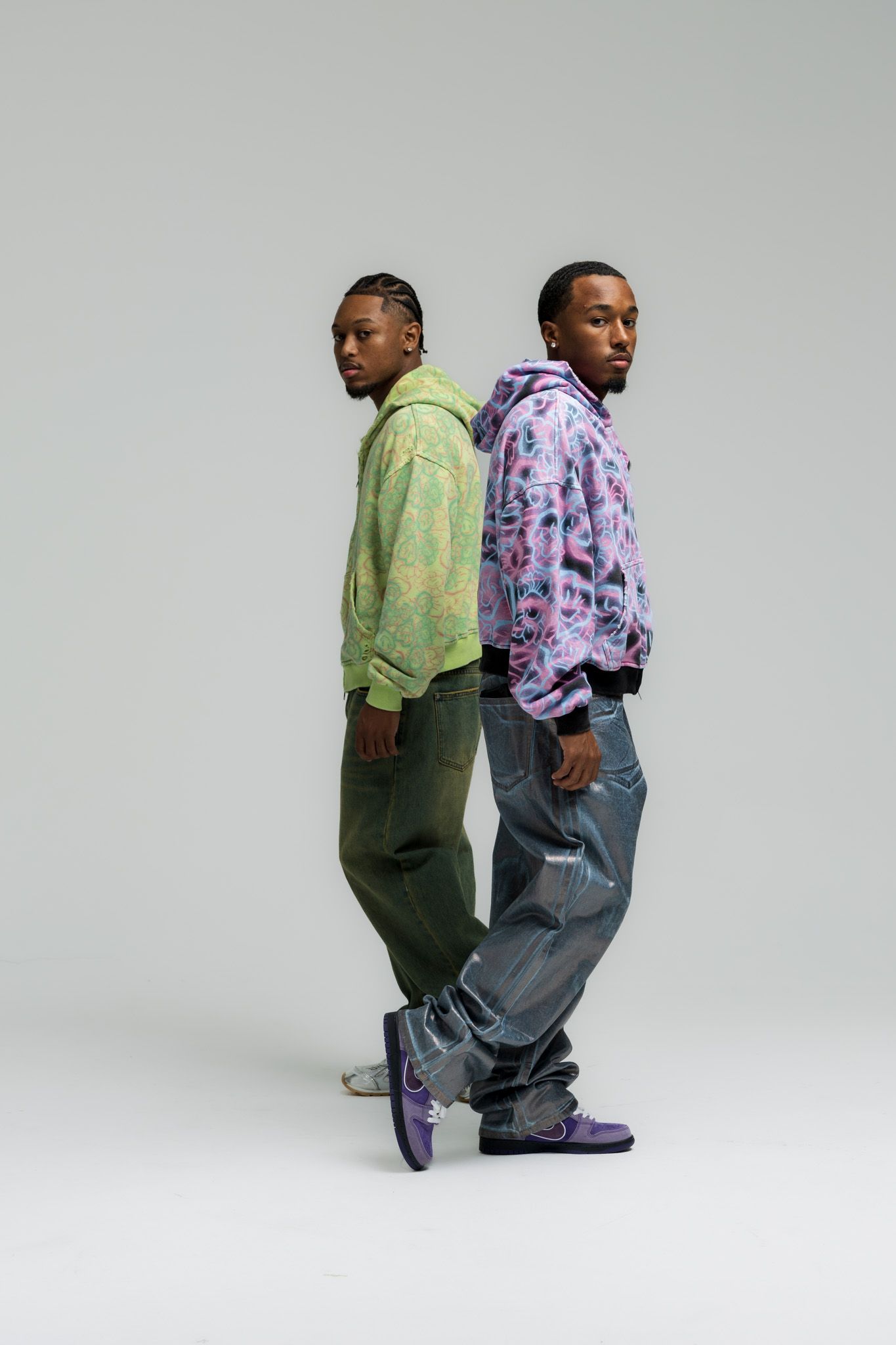 Two people in casual wear standing back to back in various poses against a light gray studio background.