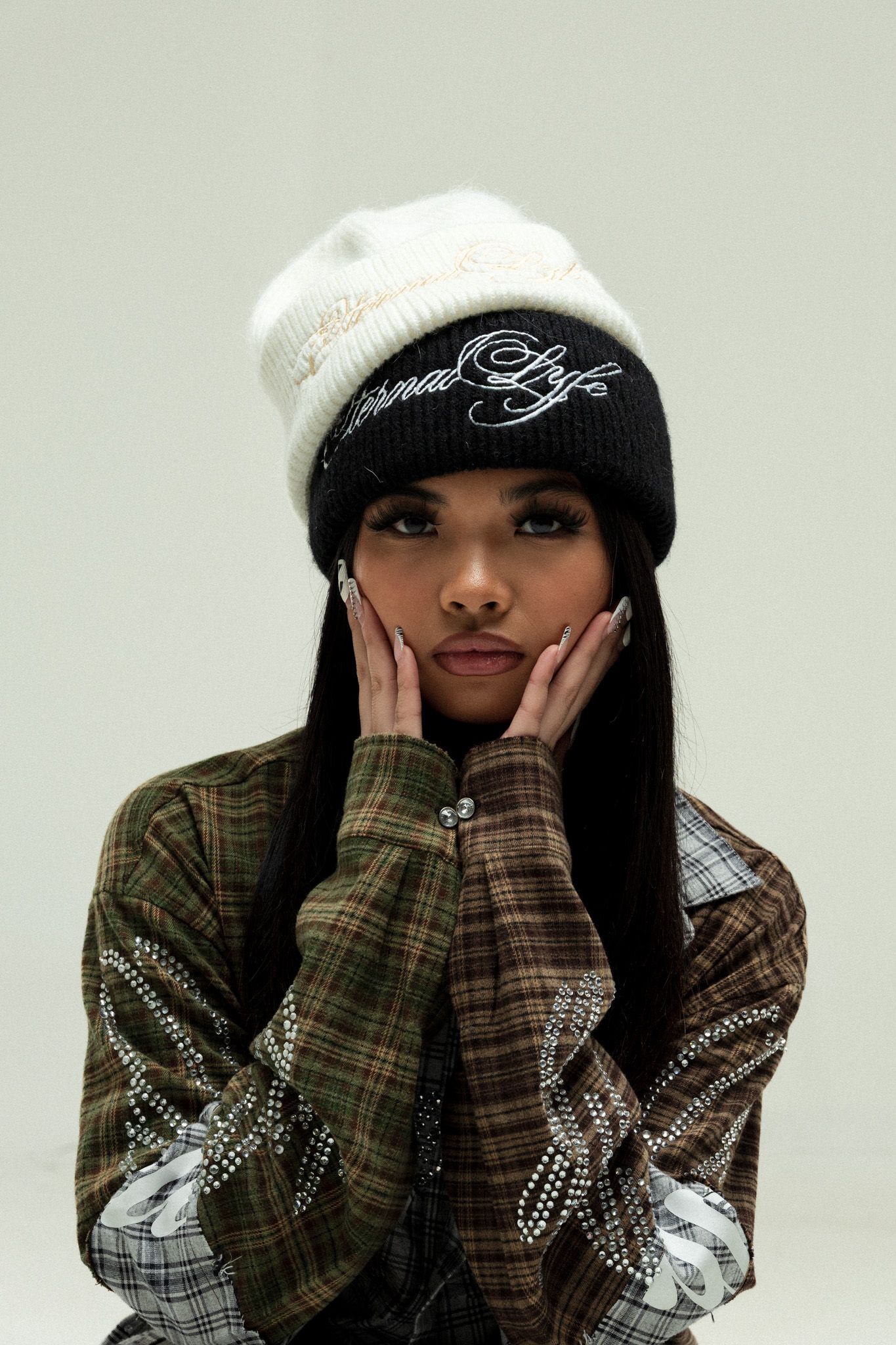 A person wearing a white knit beanie and plaid shirt poses with hands on their face in a fashion photoshoot sequence.