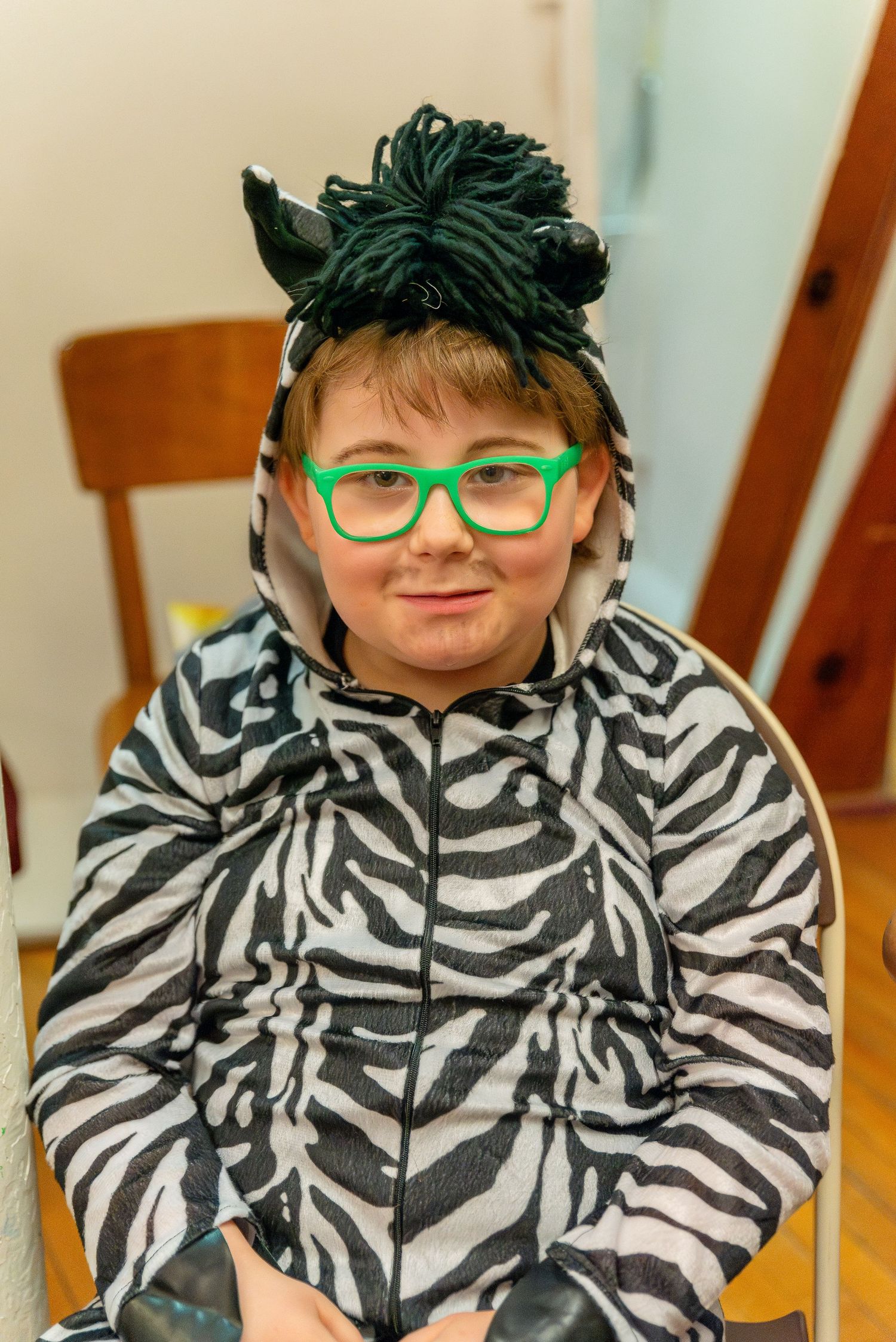 A person in a zebra print jacket and green glasses posing playfully for the camera.