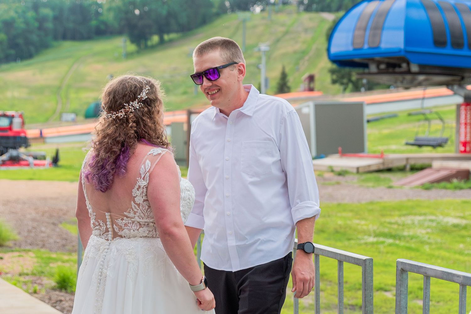 A couple walks together on a grassy hillside at a ski resort during summer.