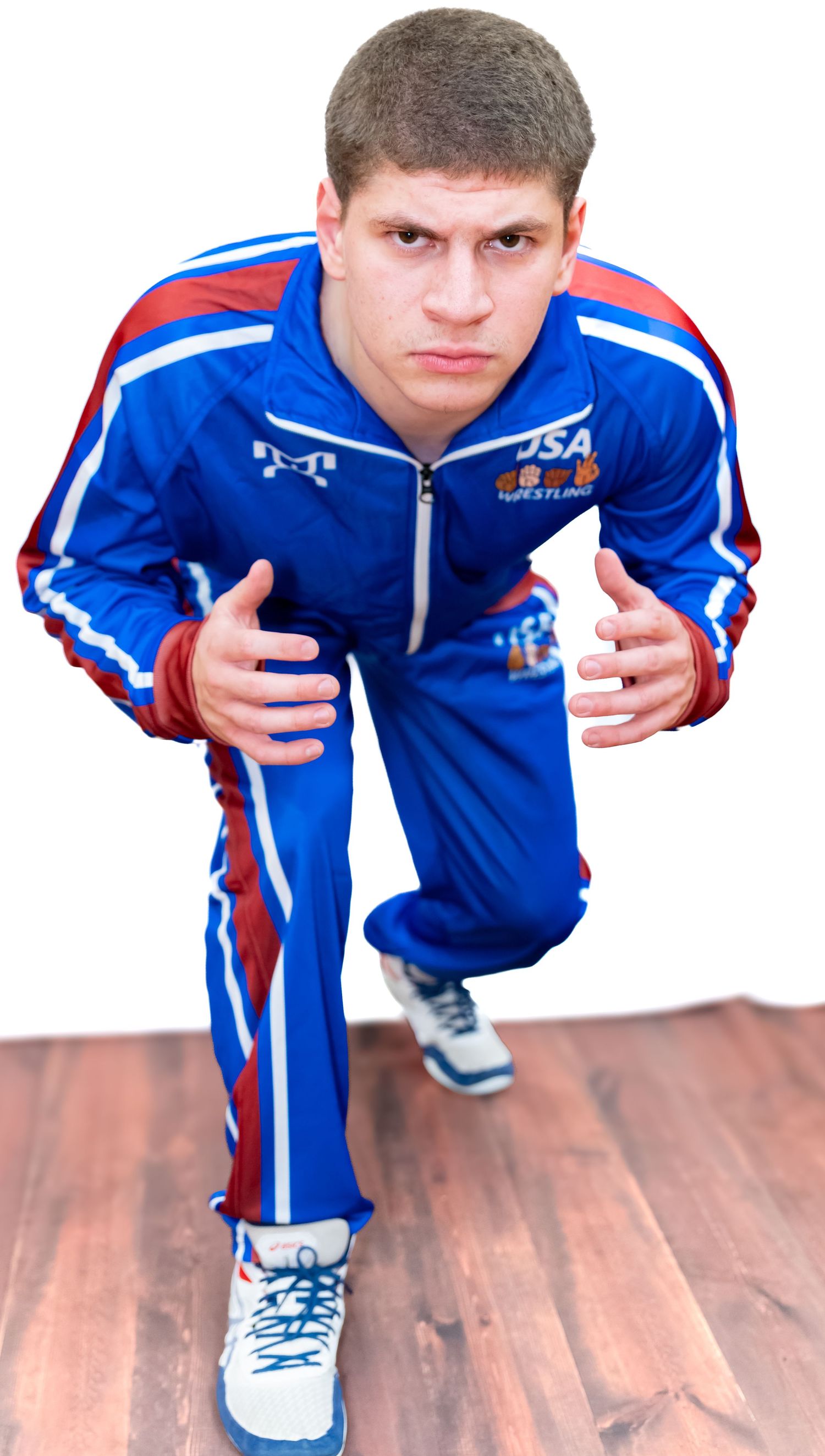 Athletic figure in blue USA team tracksuit crouches in dynamic pose on hardwood floor.