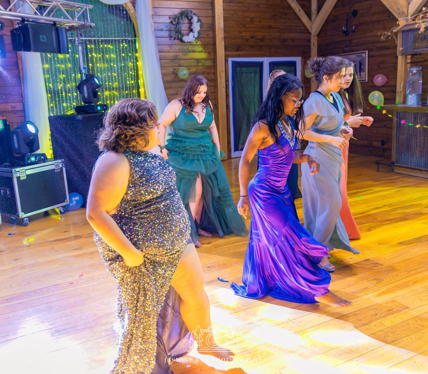 A group of dancers perform a synchronized routine on a wooden dance floor illuminated by warm lighting.