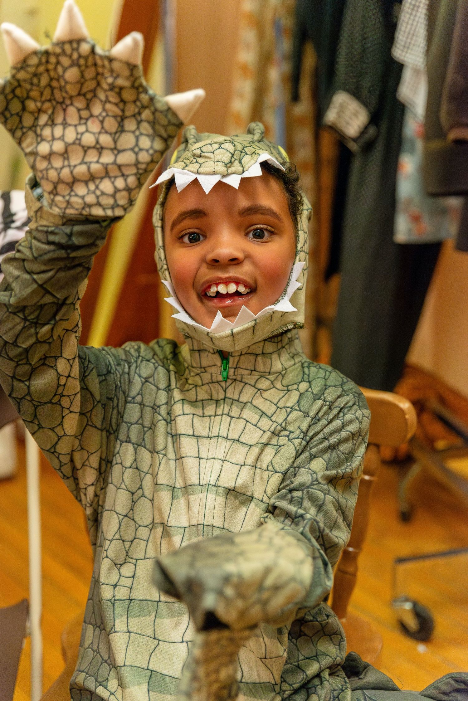 A playful dinosaur costume with scales and spikes being worn during a performance.