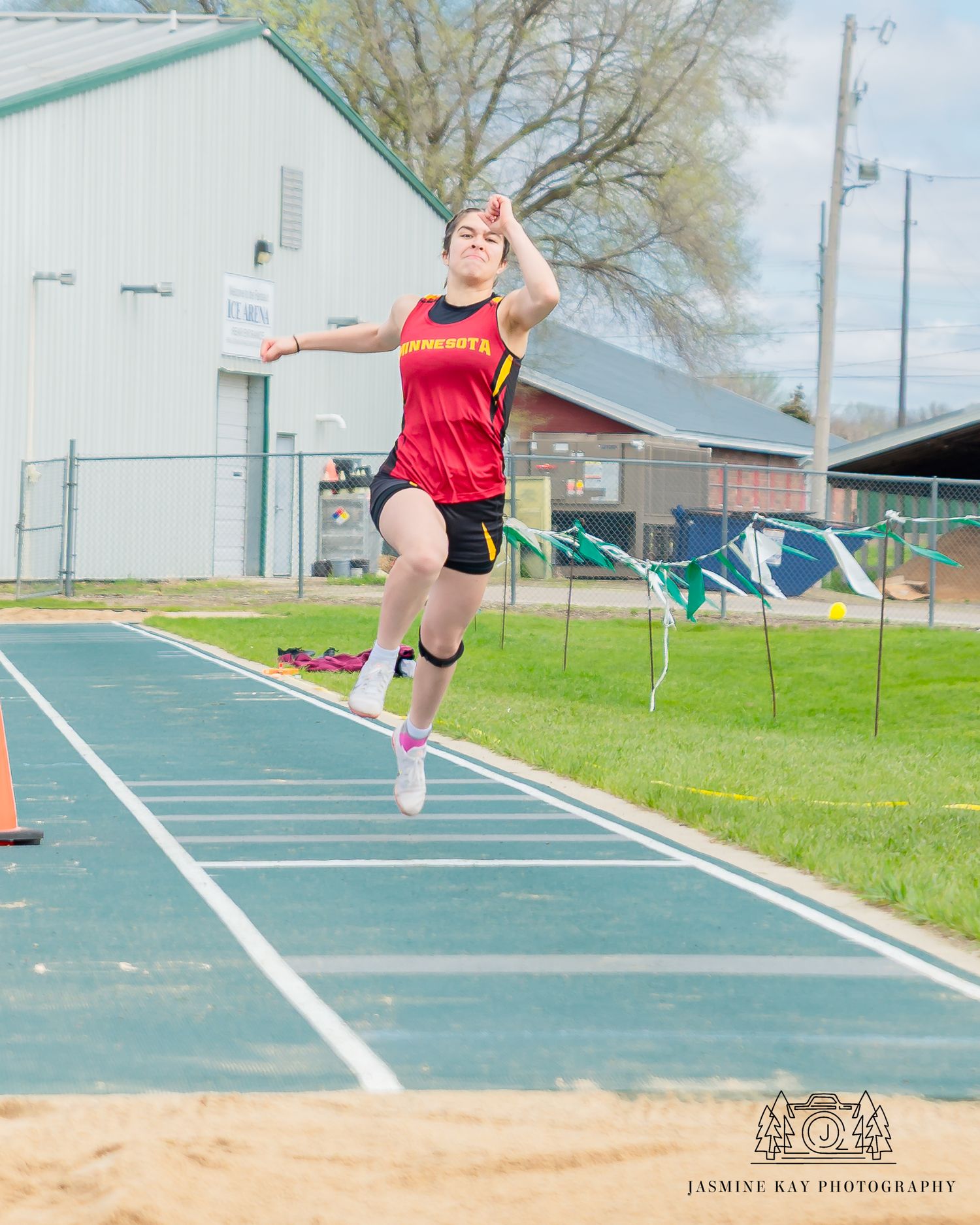 Progressive shots of an athlete performing a long jump into a sand pit on a sunny day.