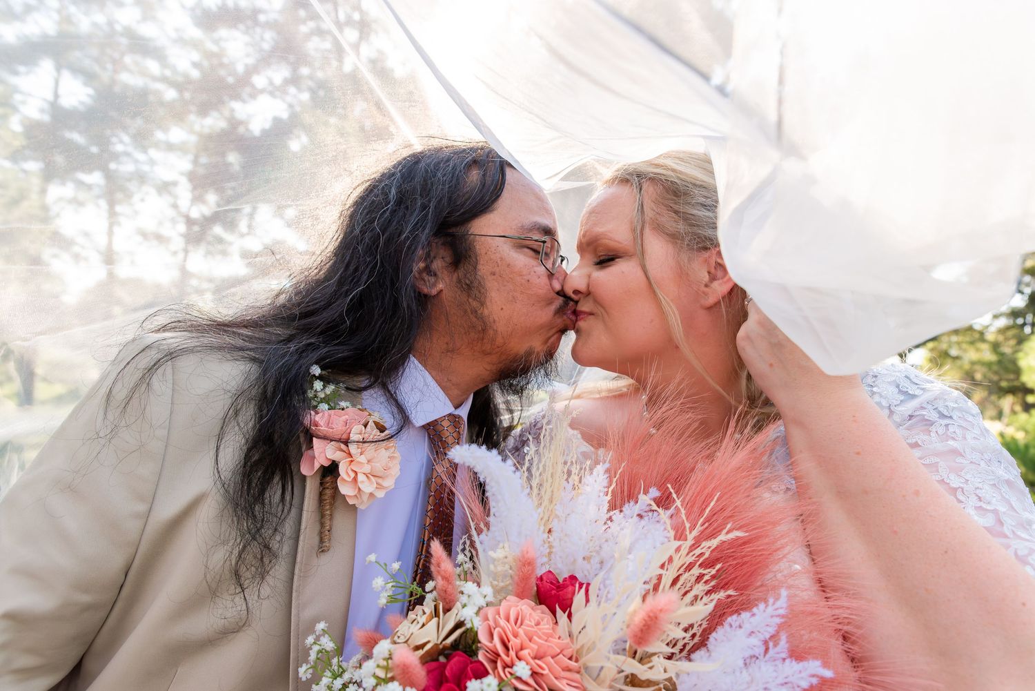 Intimate wedding portrait captured in soft misty lighting with vibrant pink bouquet.
