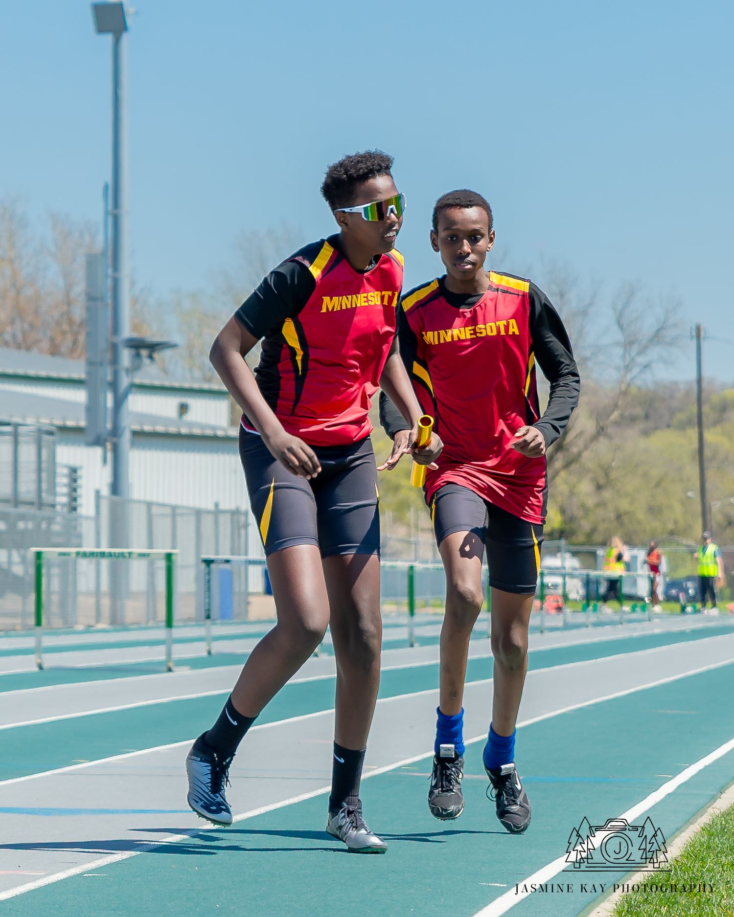 Athletes practicing running drills on a blue track during an outdoor training session.