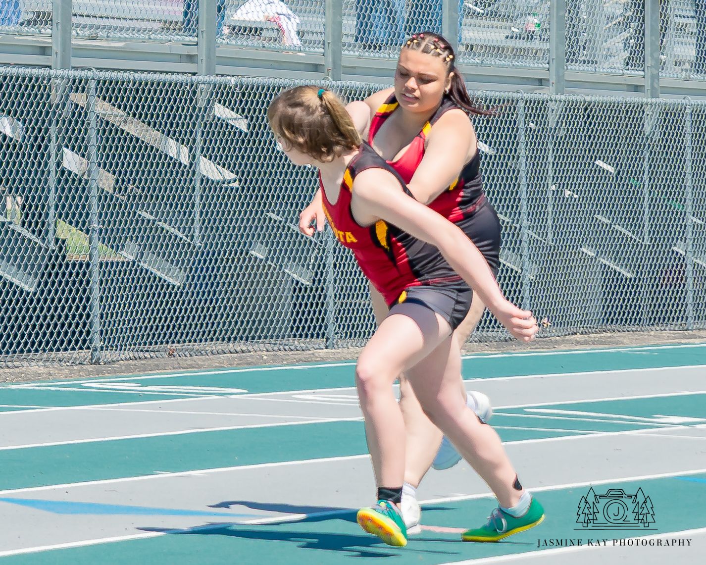 Athlete in red uniform performs a dynamic long jump sequence on an outdoor track.