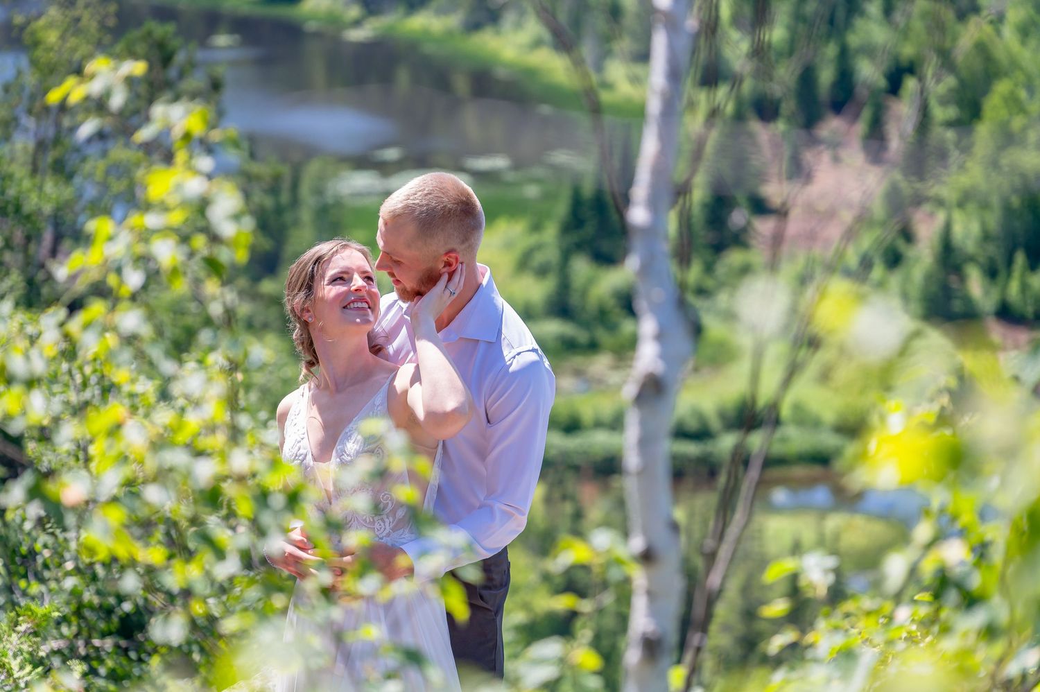 A couple shares a joyful embrace among yellow wildflowers with a lake view in the background.
