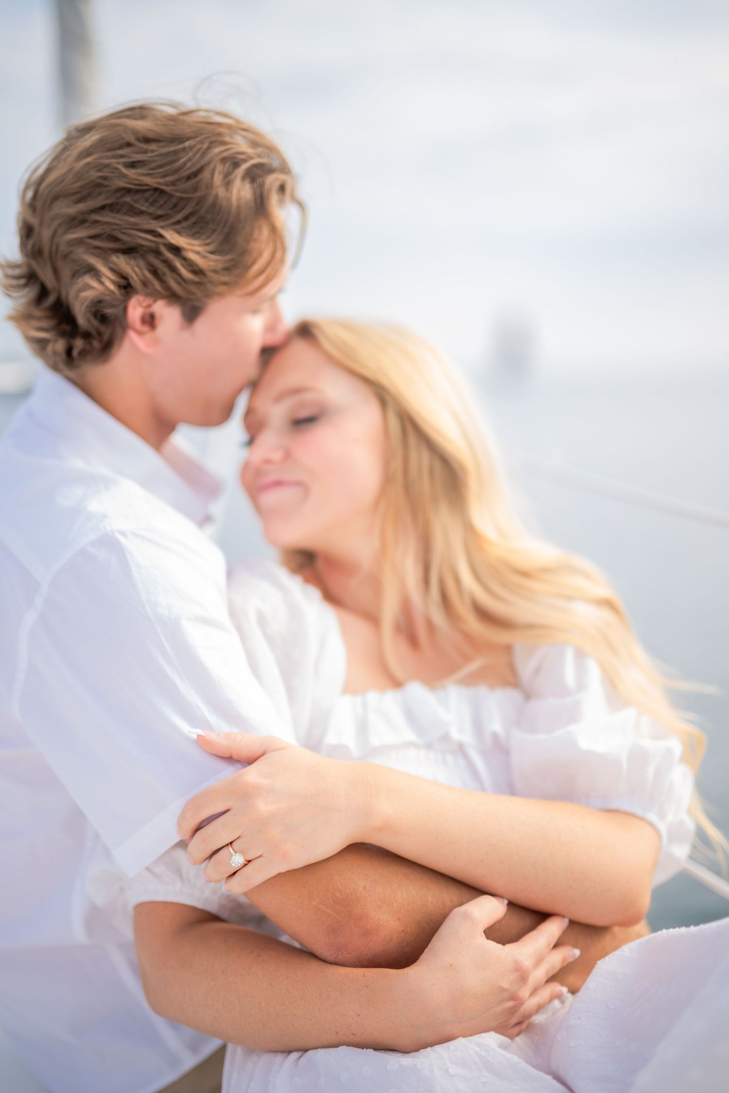 An intimate embrace captured on a sailboat with soft lighting and romantic atmosphere.