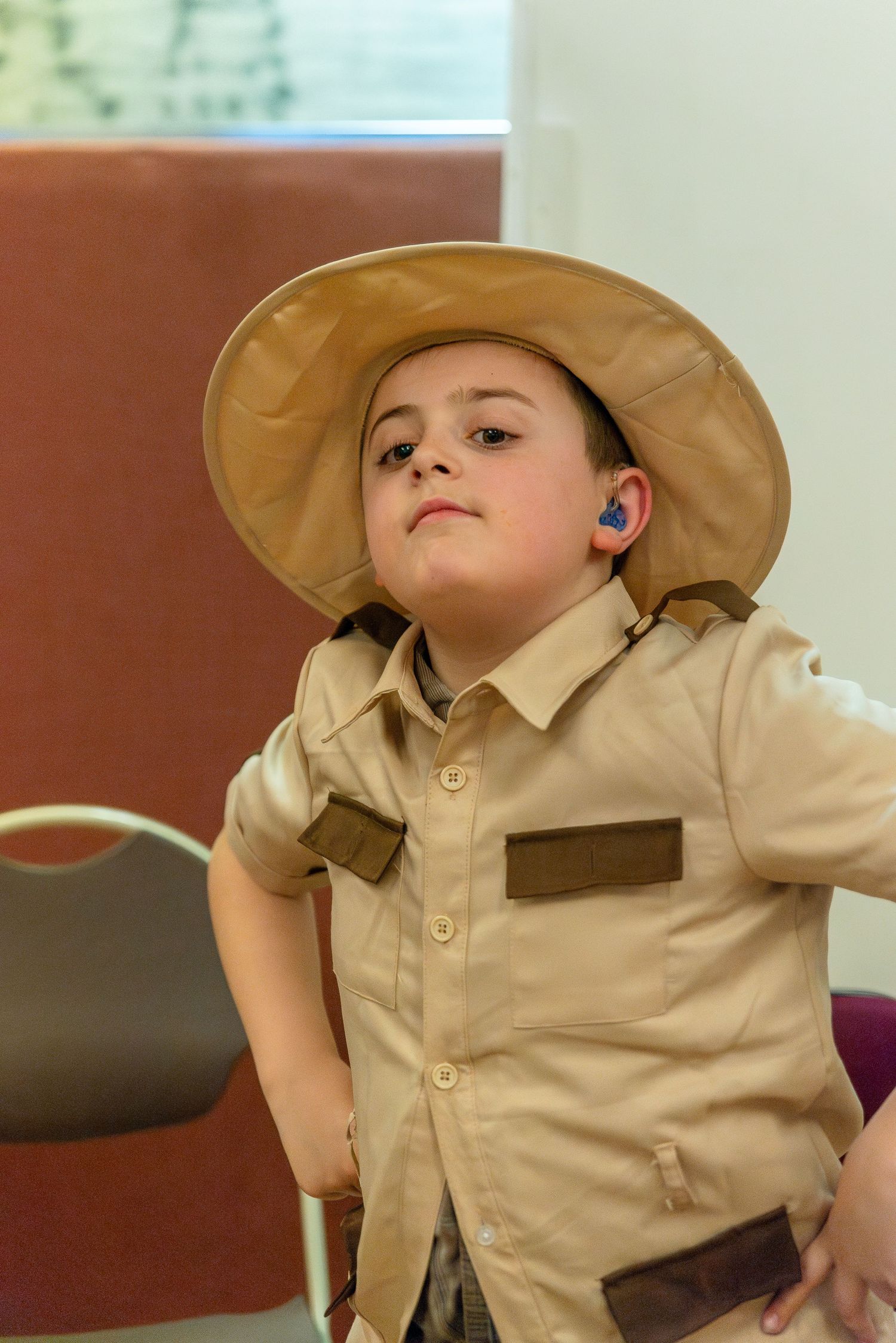 Young performer in a tan safari outfit and hat during a stage play.