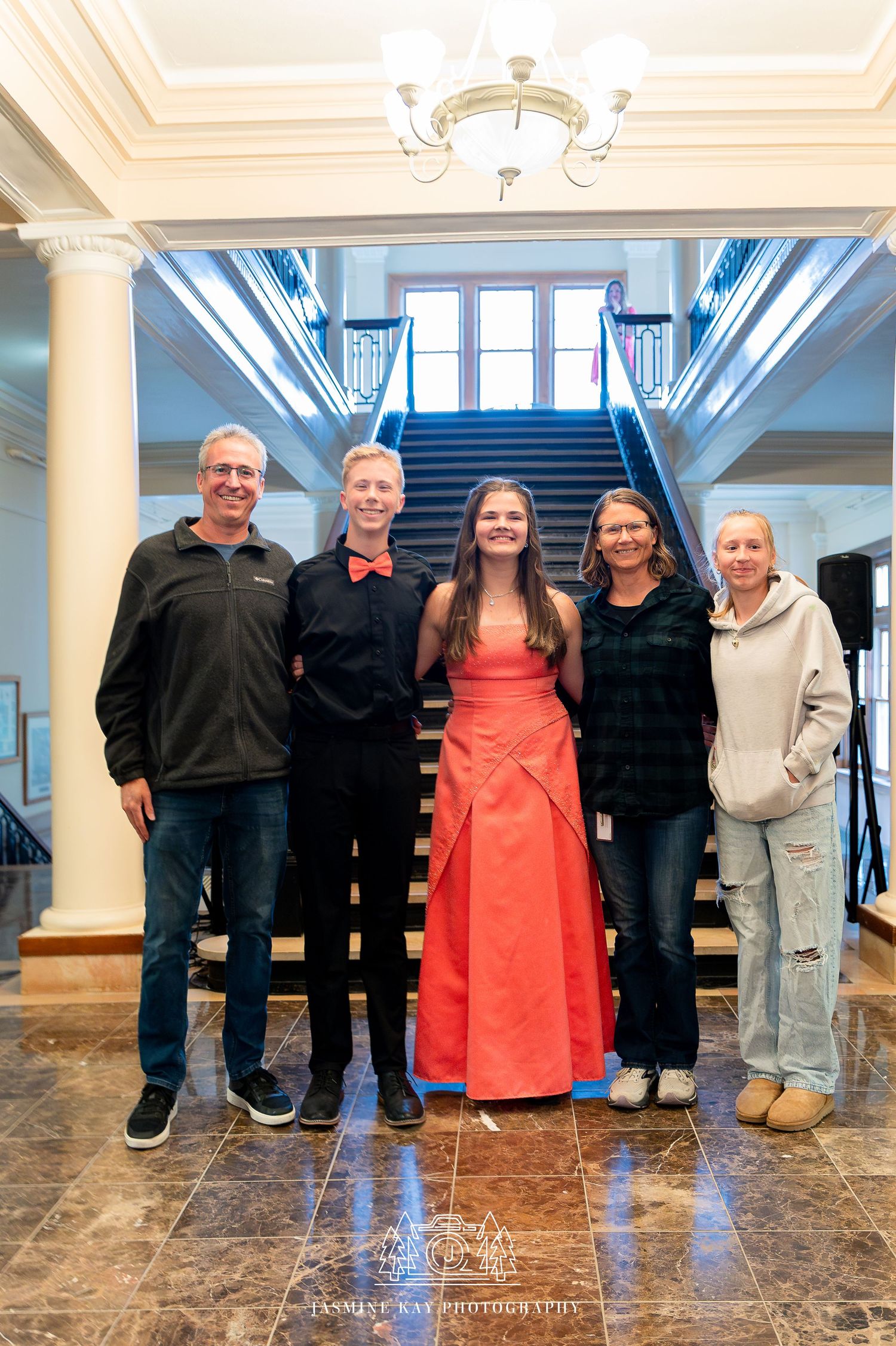 A group of people stand together in an elegant lobby with marble floors and white columns.