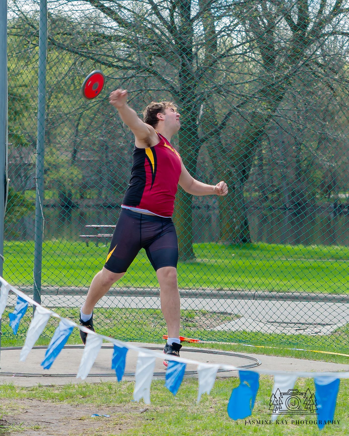 Sequential action shots of an athlete performing a long jump over blue hurdles on an outdoor track.