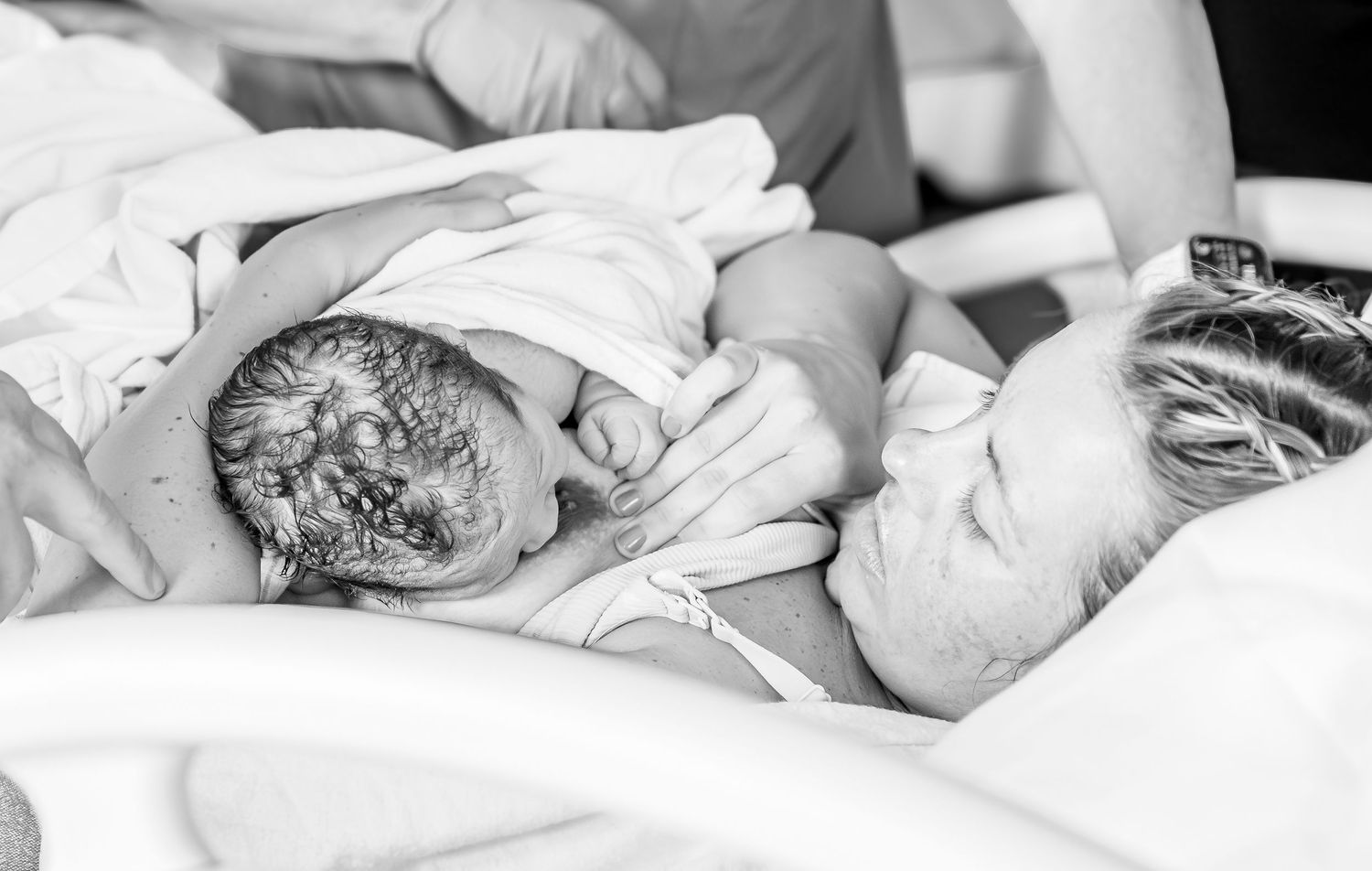 A black and white photo of a sleeping newborn baby wrapped in soft blankets.