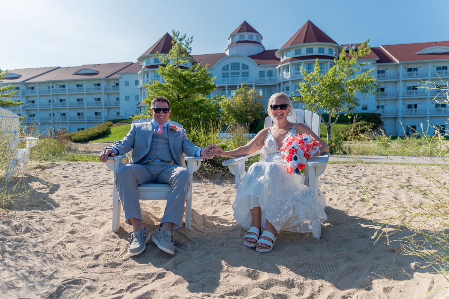 Couple relaxing in beach chairs with resort building in background.