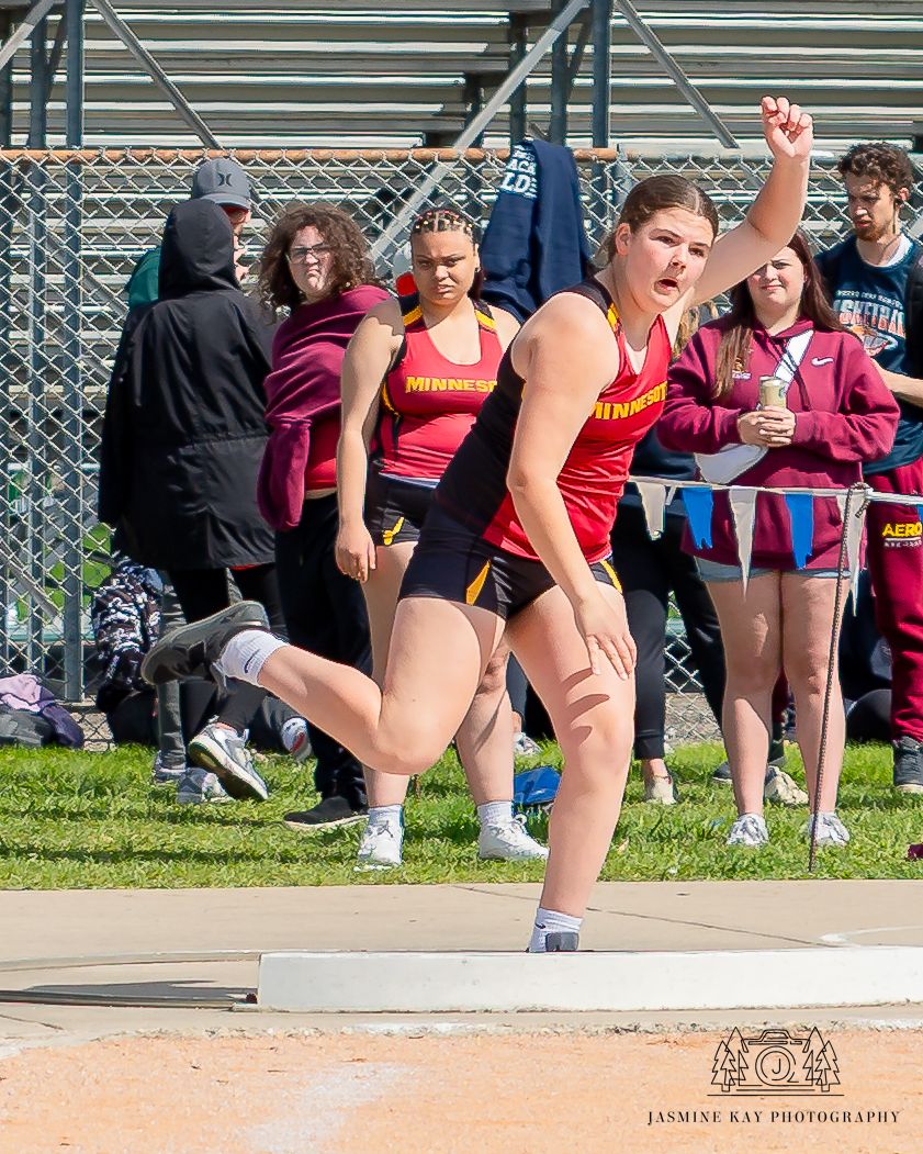Track and field athlete performs a long jump at an outdoor competition, landing in the sand pit.