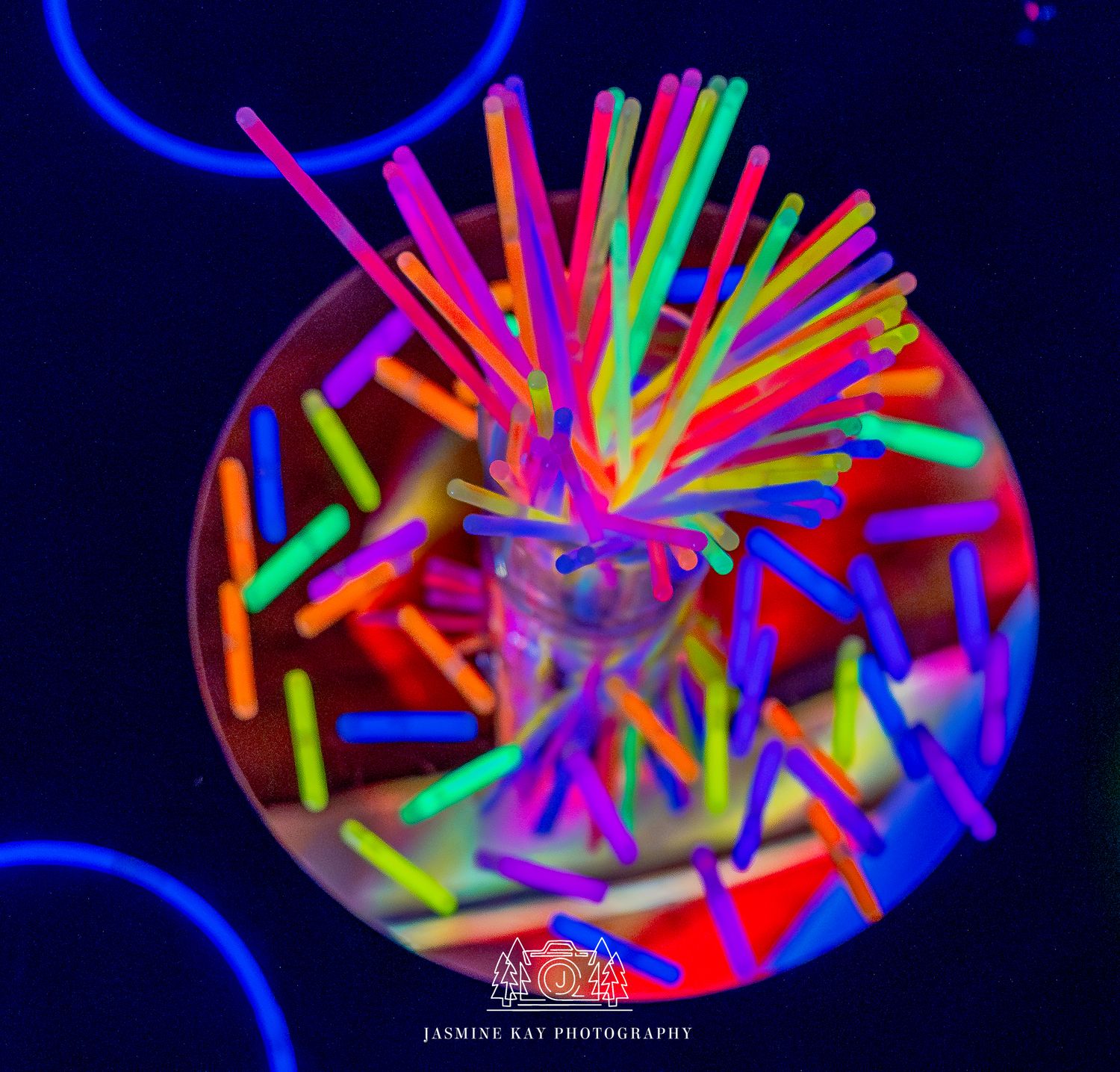 A time-lapse sequence showing colorful neon light trails forming a spiral pattern against a dark background.