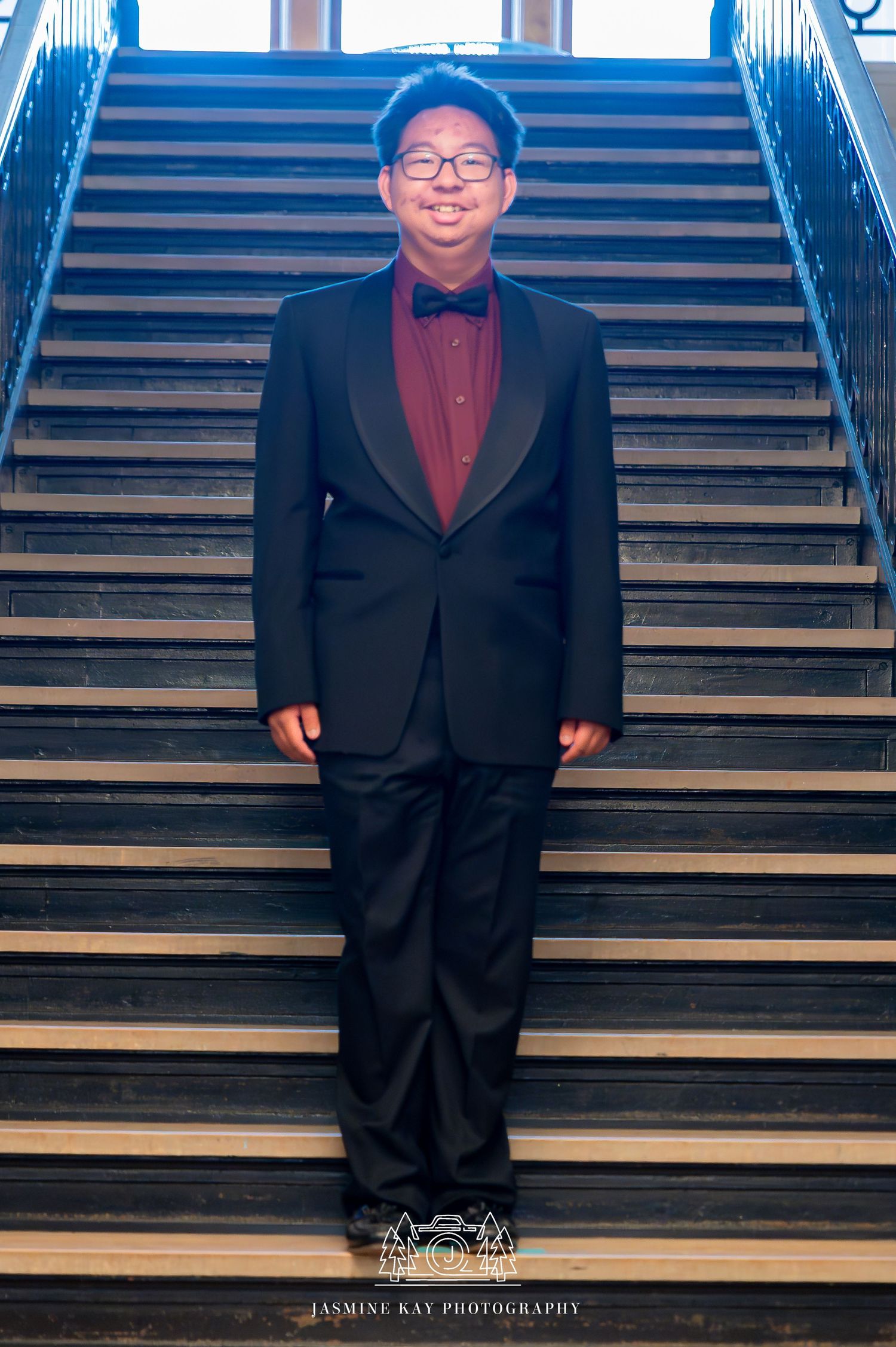 Professional portrait series showing person in dark suit standing on wooden stairs with blue lighting.