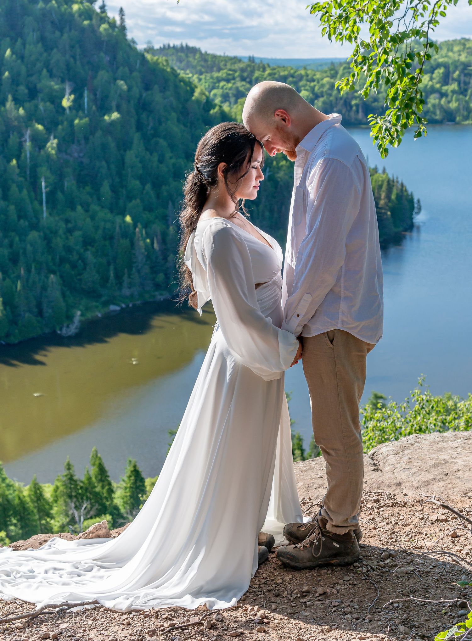 A romantic wedding couple shares an intimate moment on a cliff overlooking a scenic forest lake Johnson.