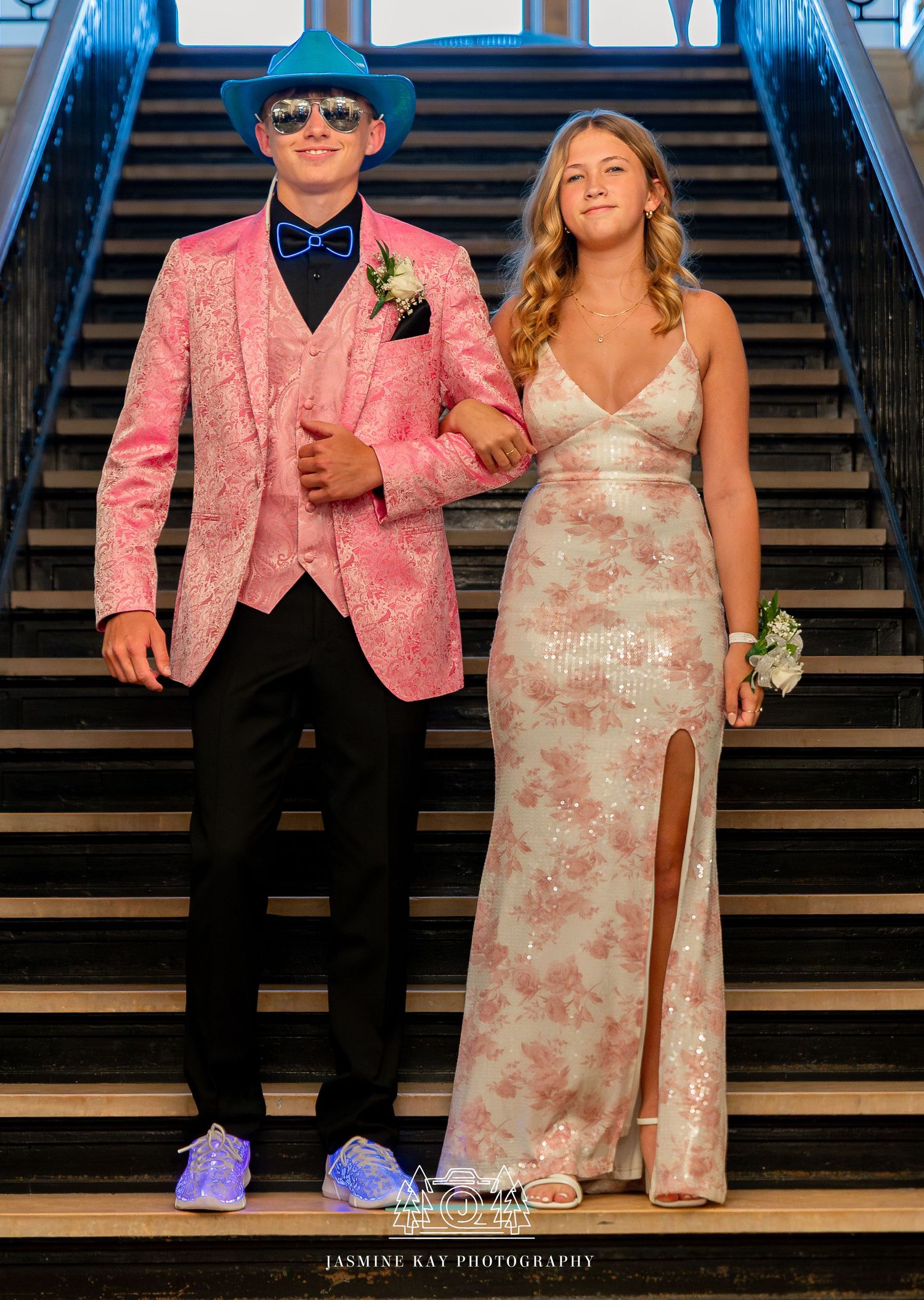 Couple poses on wooden stairs in coordinating pink floral attire during a wedding photo session.