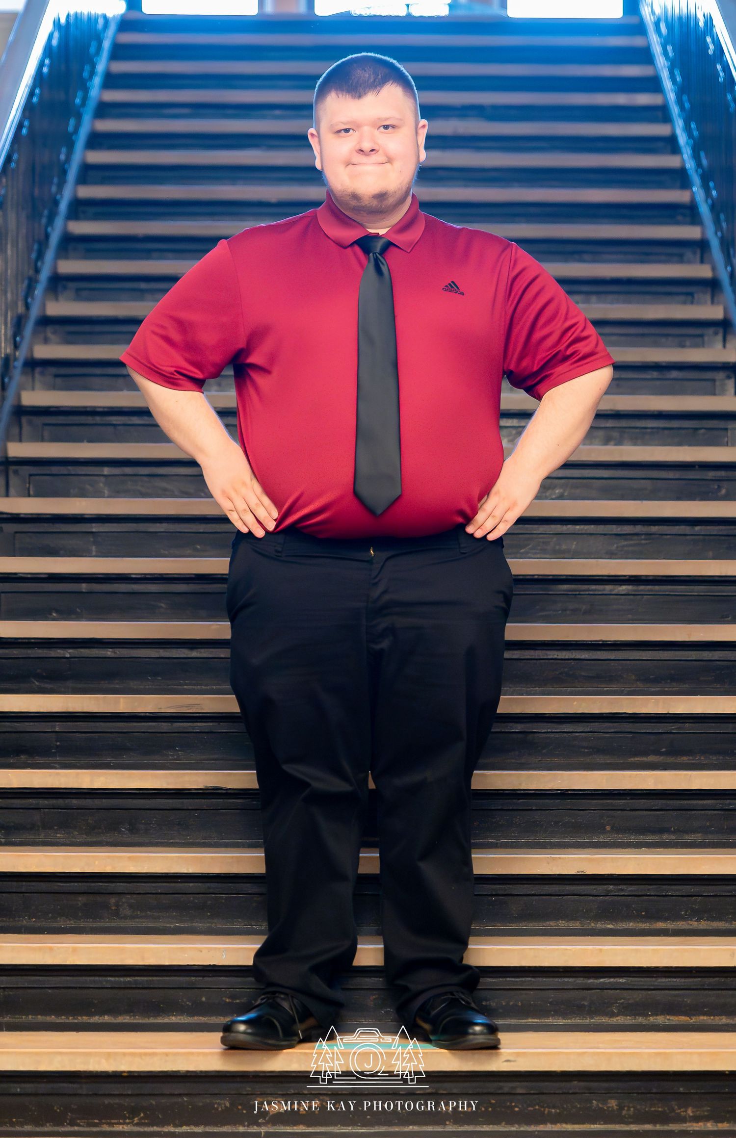 A composite photo showing four identical poses of someone in a red shirt and black tie standing on wooden stairs.