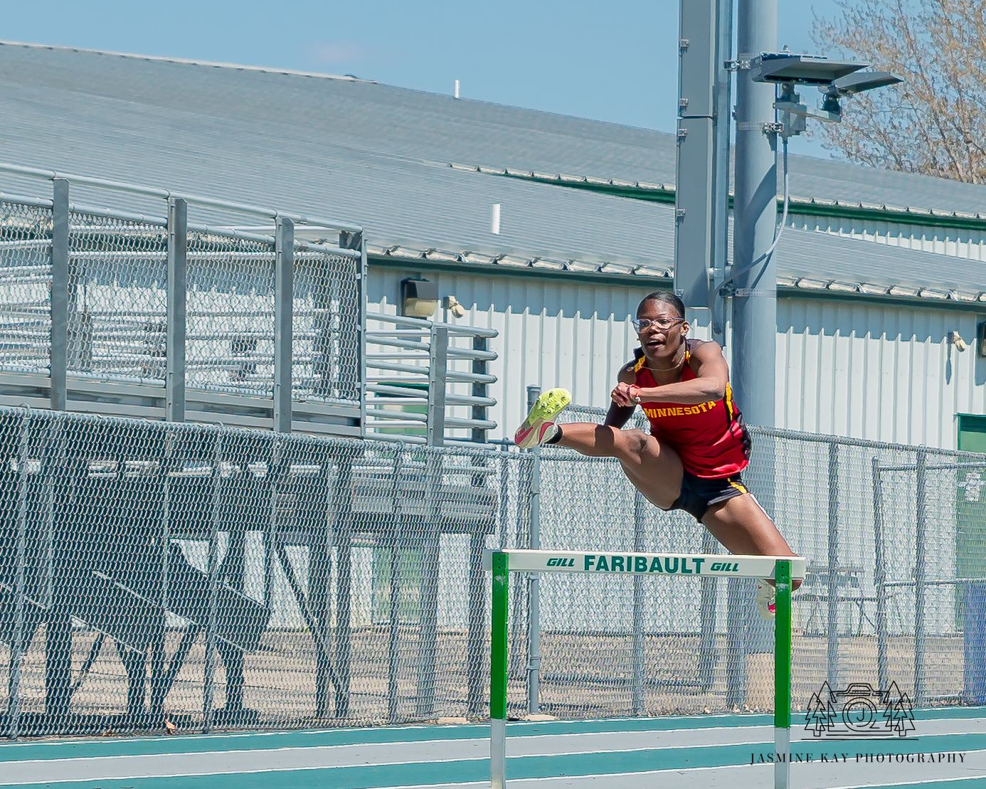 Track athlete leaping over hurdle during outdoor competition.