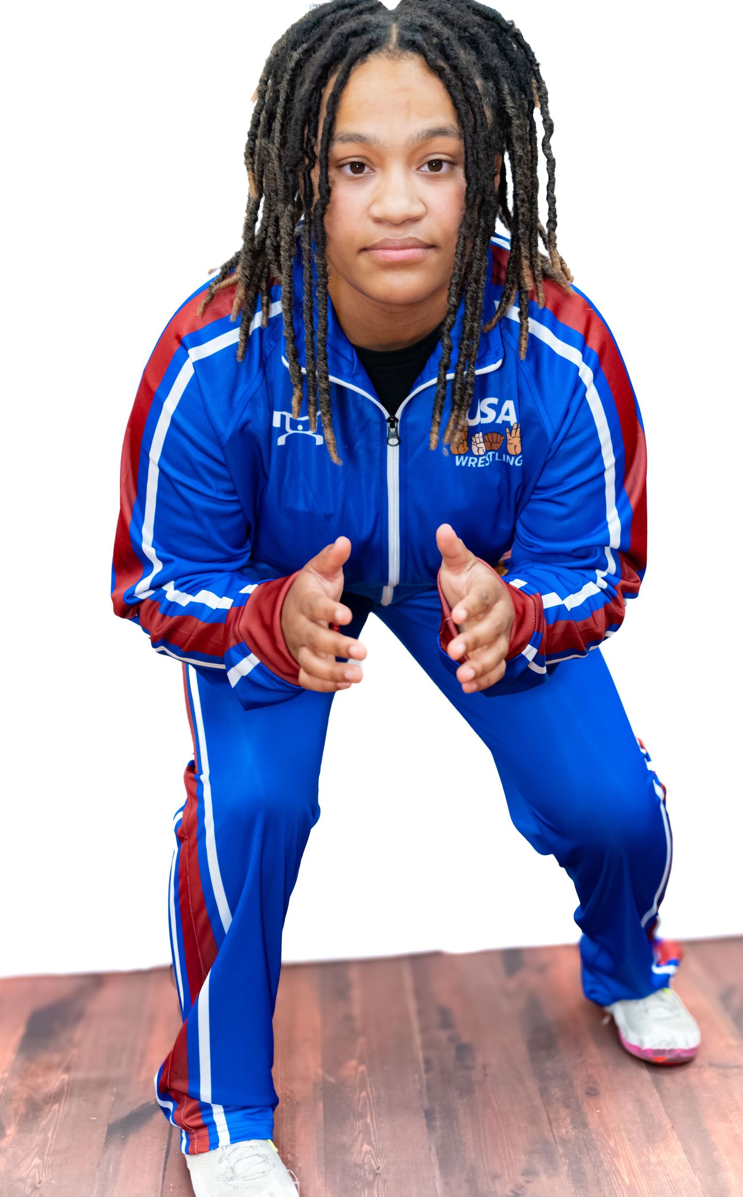 Person in blue and red tracksuit striking different poses on hardwood floor.