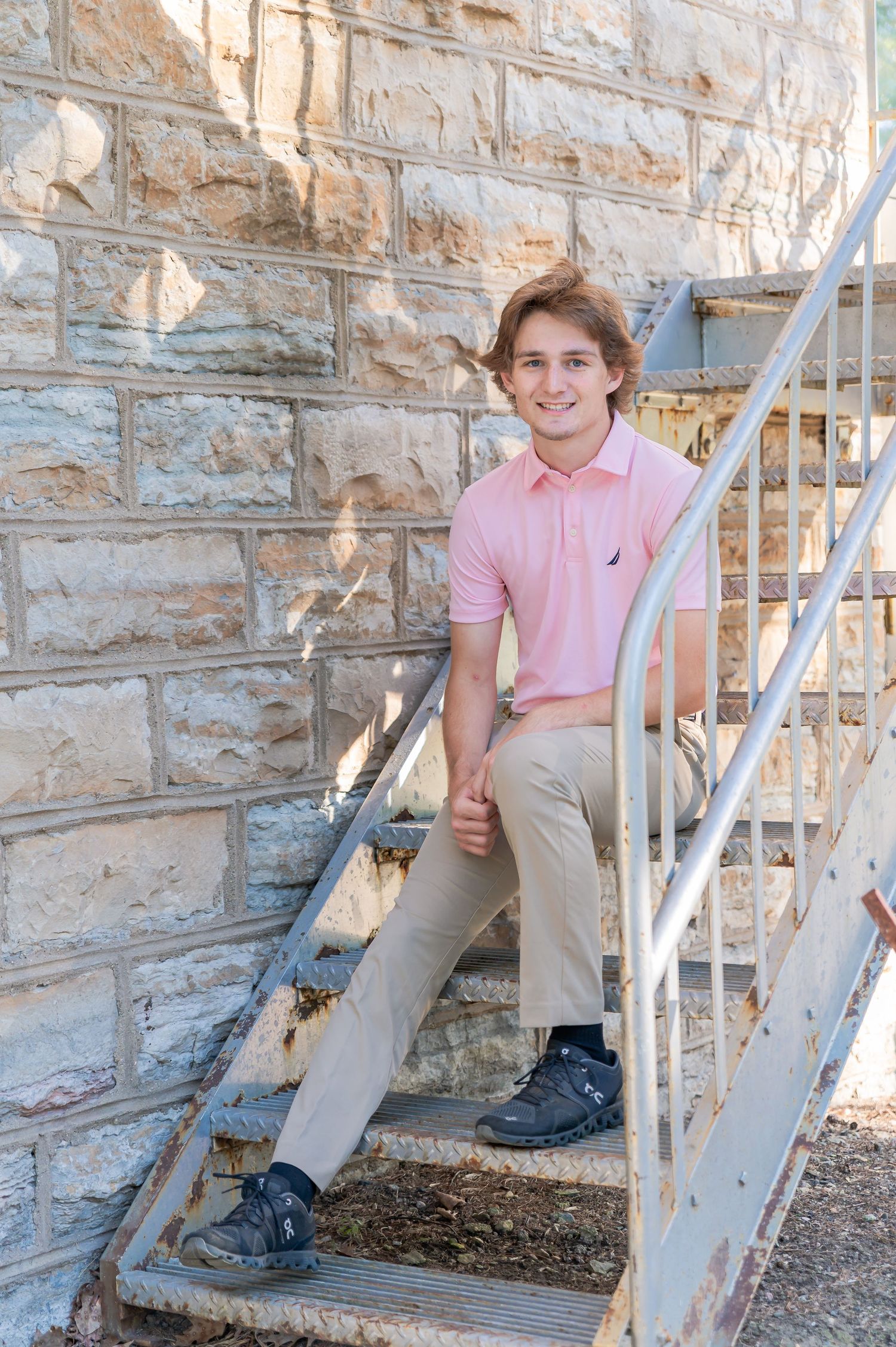 A person in a pink polo shirt and khaki pants sits casually on outdoor stone steps in multiple poses.