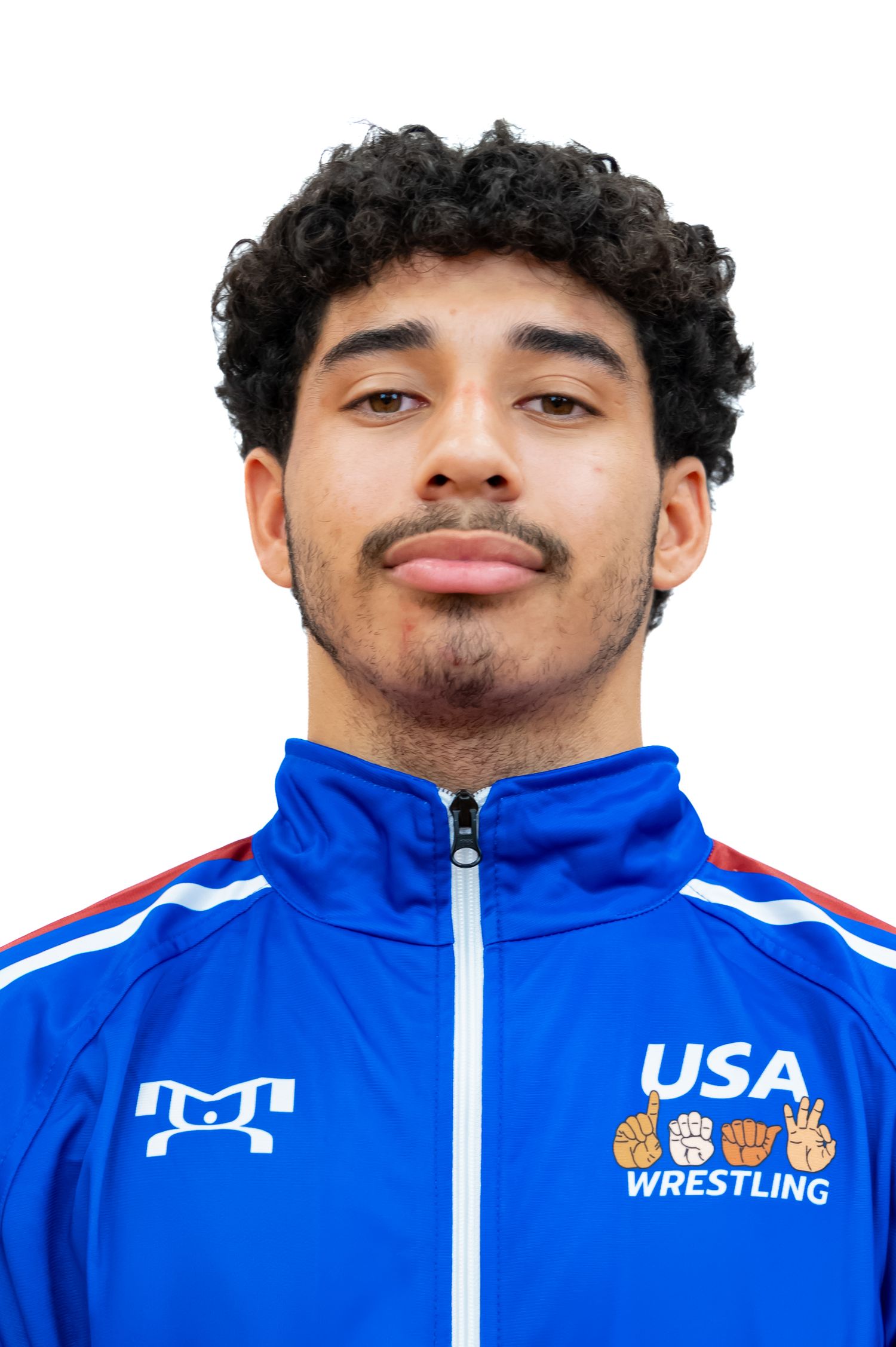 Profile view of a team member wearing a blue USA Wrestling jacket with dark curly hair.