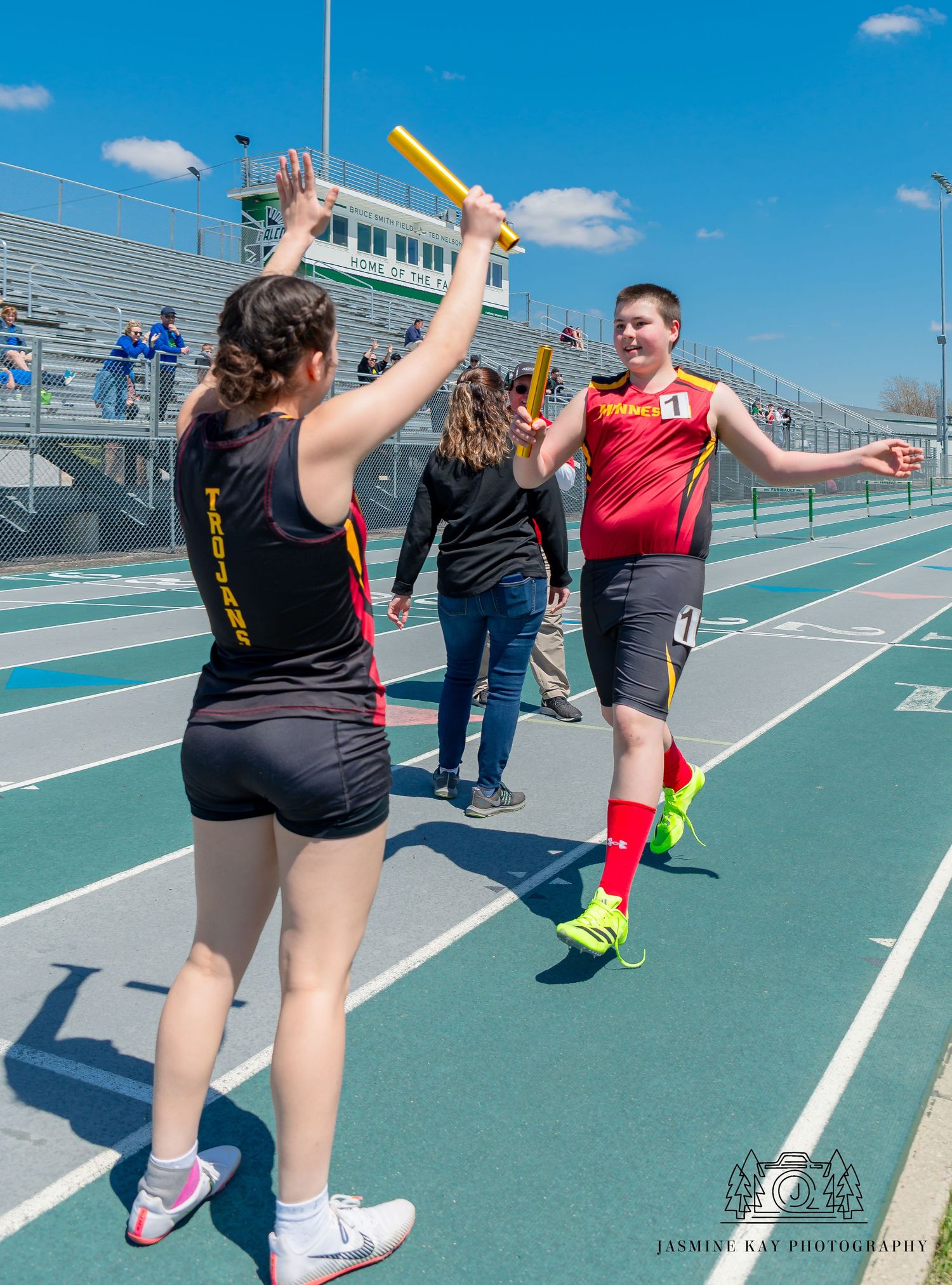 Athletes practicing relay race baton handoffs on an outdoor track during training.