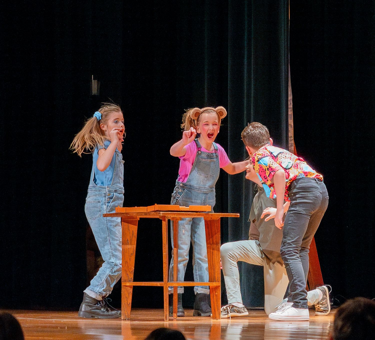 Performers on stage demonstrate dynamic dance moves using wooden chairs as props during a theatrical performance.
