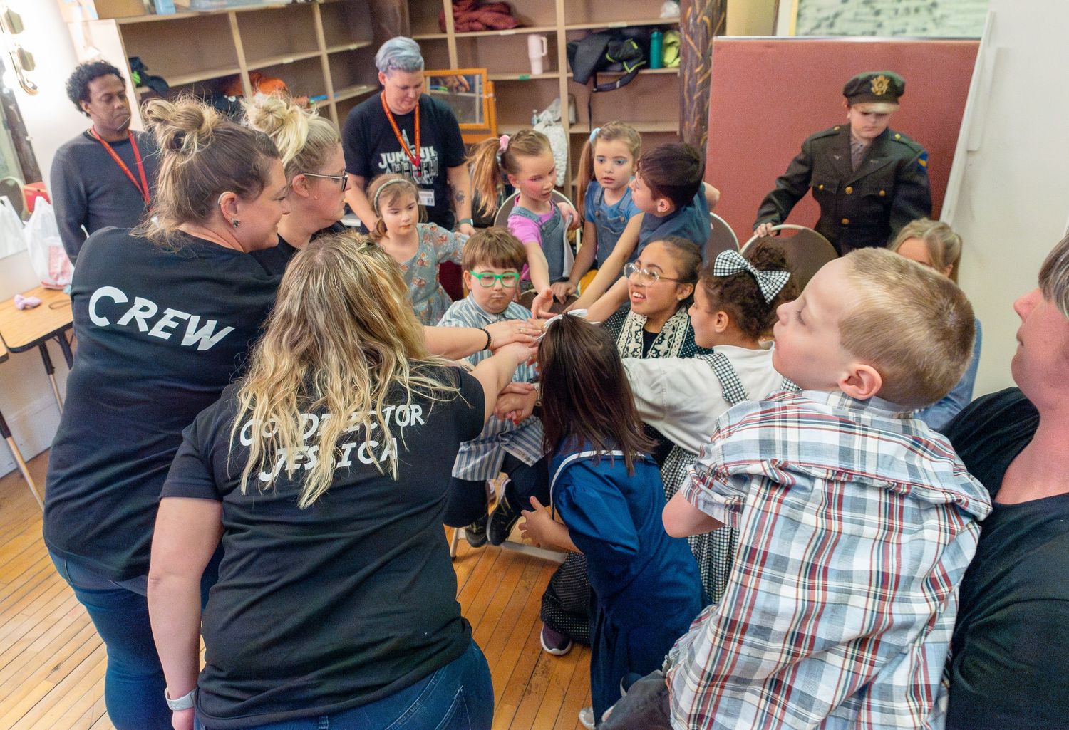 Theater crew and cast members interact backstage during a performance preparation.