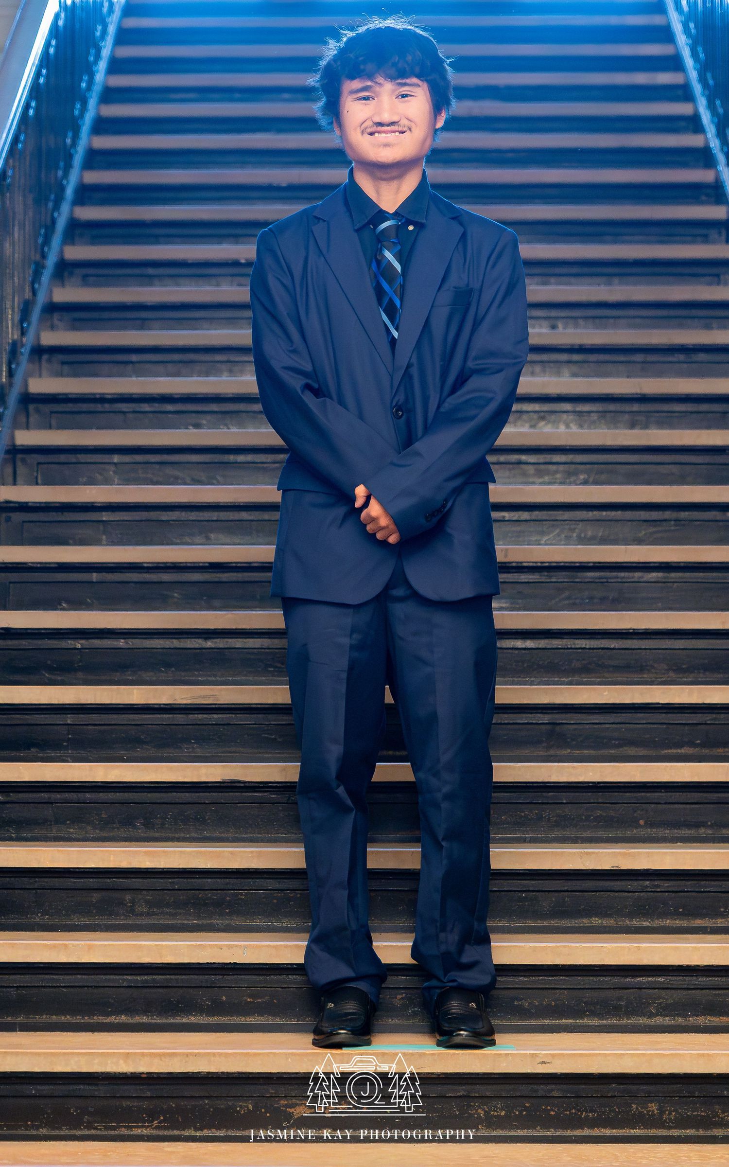 A person wearing a dark suit sits on wooden stairs in a sequence of artistic portrait poses.
