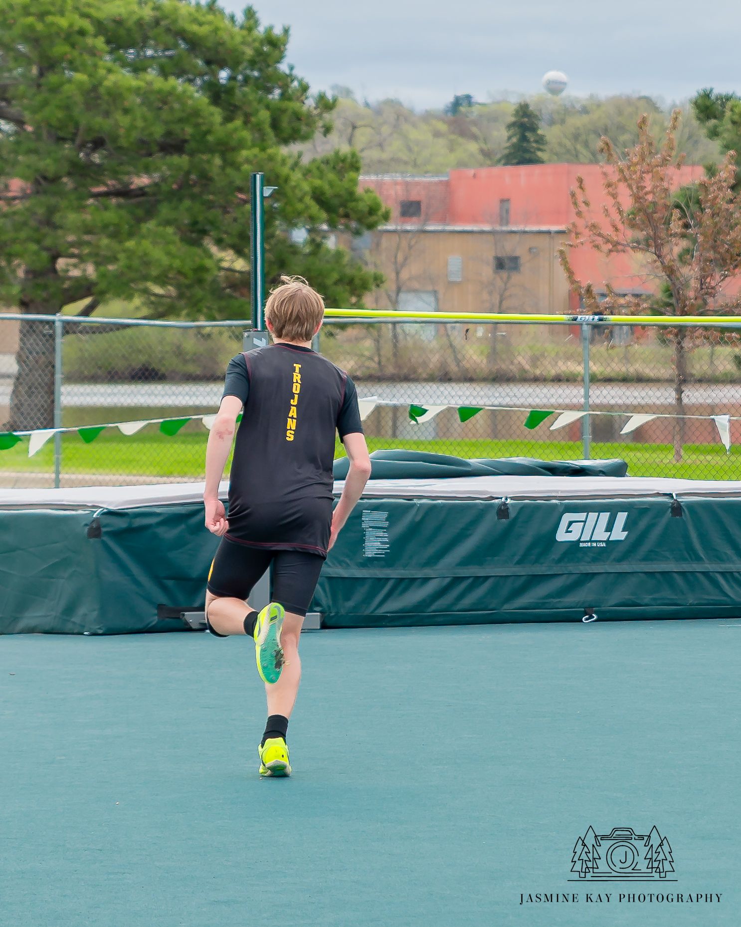 Sequence of a long jump athlete running and leaping on an outdoor track with green padding.